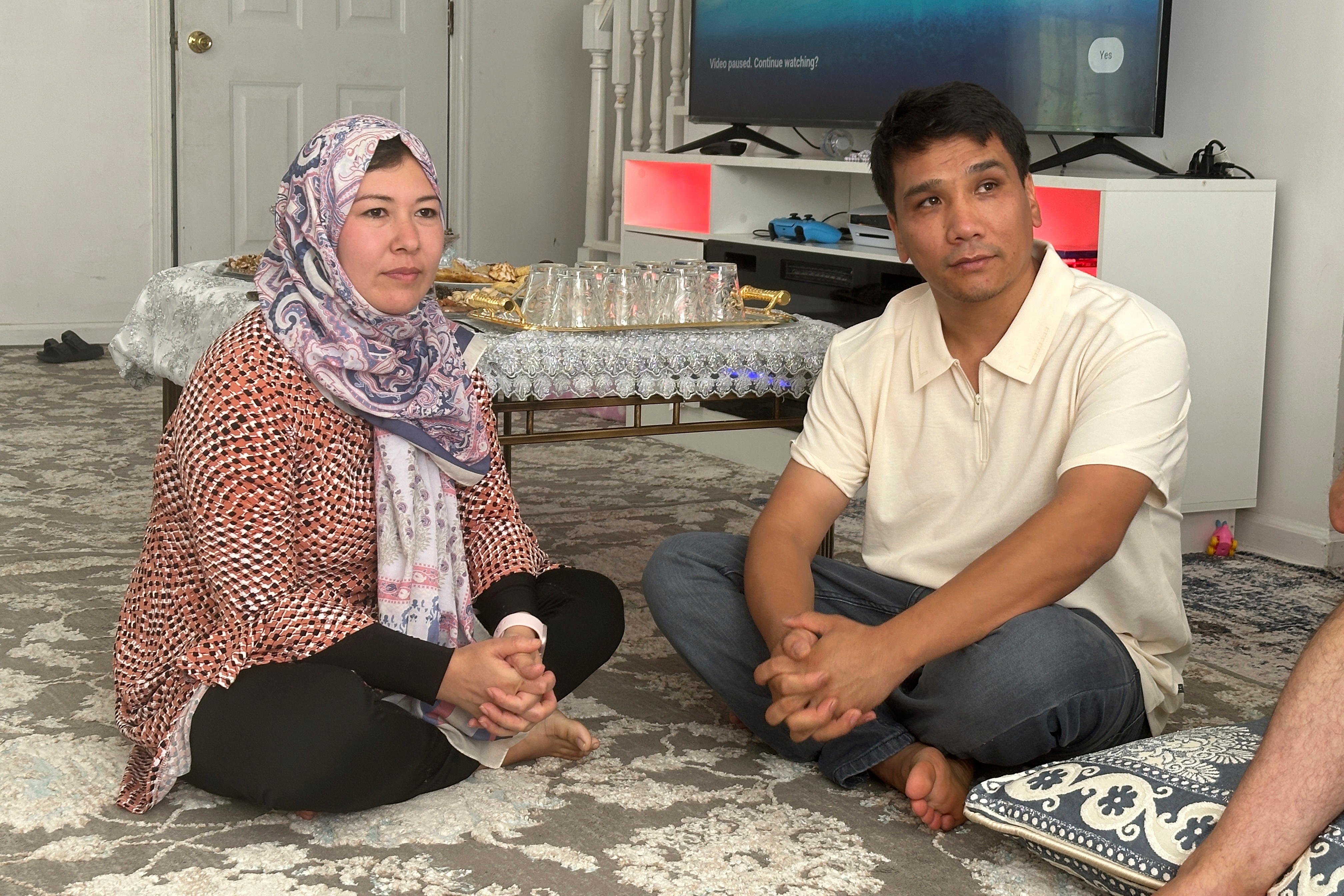Nuriya Sharafoddin, left, and her husband, Mohammad Sharafoddin, right listen to a friend talking about the travel ban from Afghanistan to the U.S. at their home in Irmo, S.C., on Saturday, June 7 2025. (AP Photo/Jeffrey Collins)