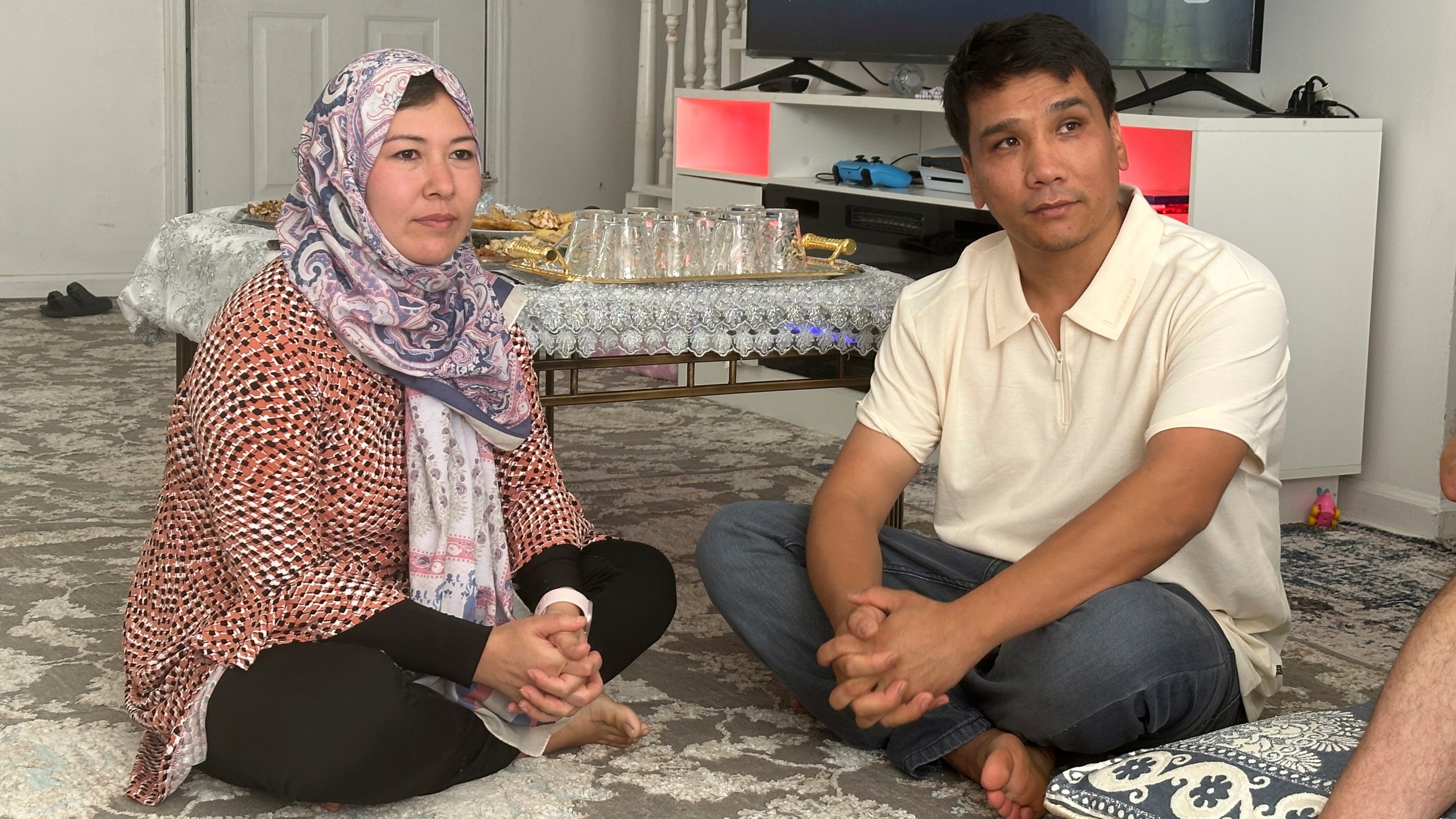 Nuriya Sharafoddin, left, and her husband, Mohammad Sharafoddin, right listen to a friend talking about the travel ban from Afghanistan to the U.S. at their home in Irmo, S.C., on Saturday, June 7 2025. (AP Photo/Jeffrey Collins)