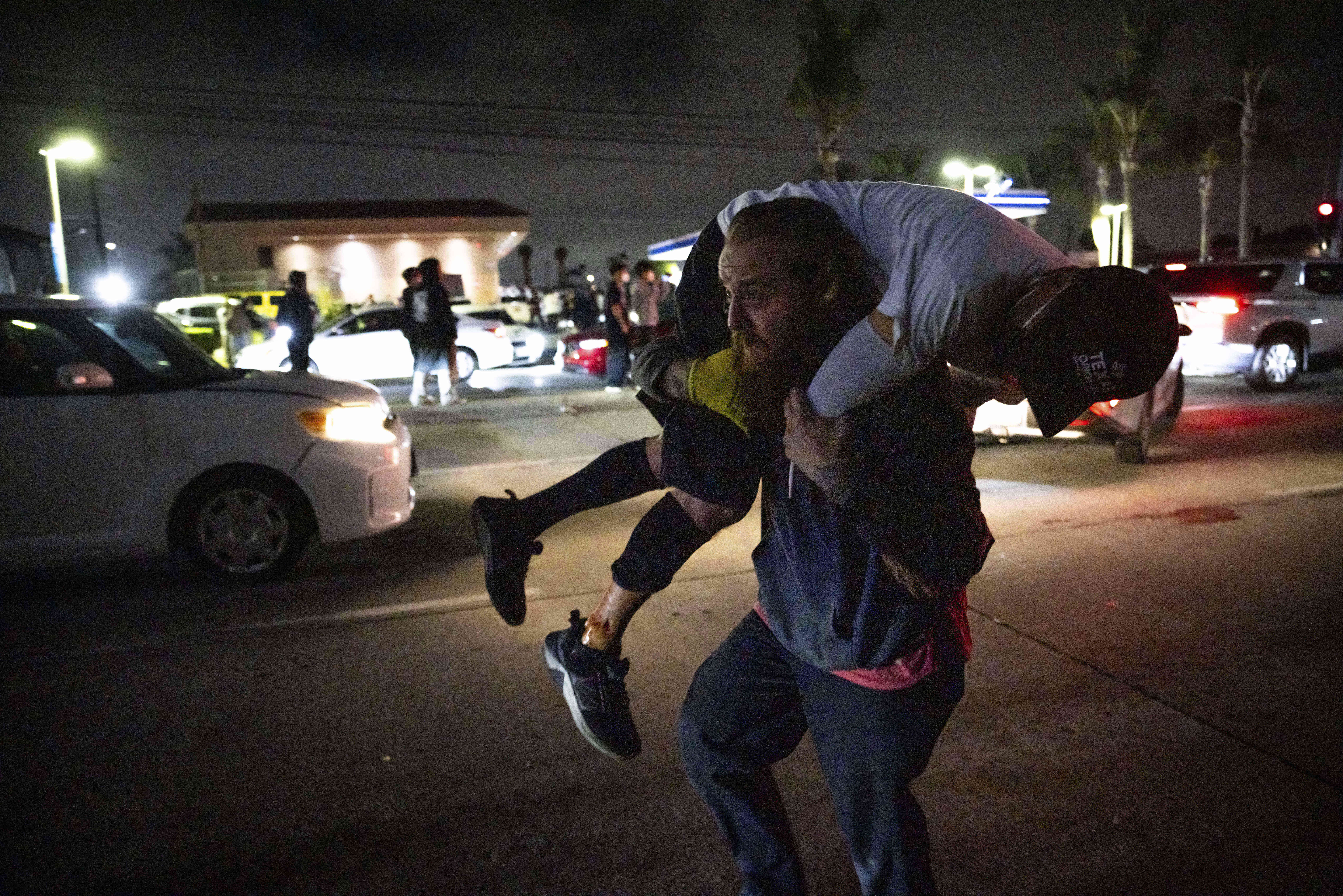 A person carries an injured protester to cover during a protest in Compton, Calif., Saturday, June 7, 2025, after federal immigration authorities conducted operations. (AP Photo/Ethan Swope)