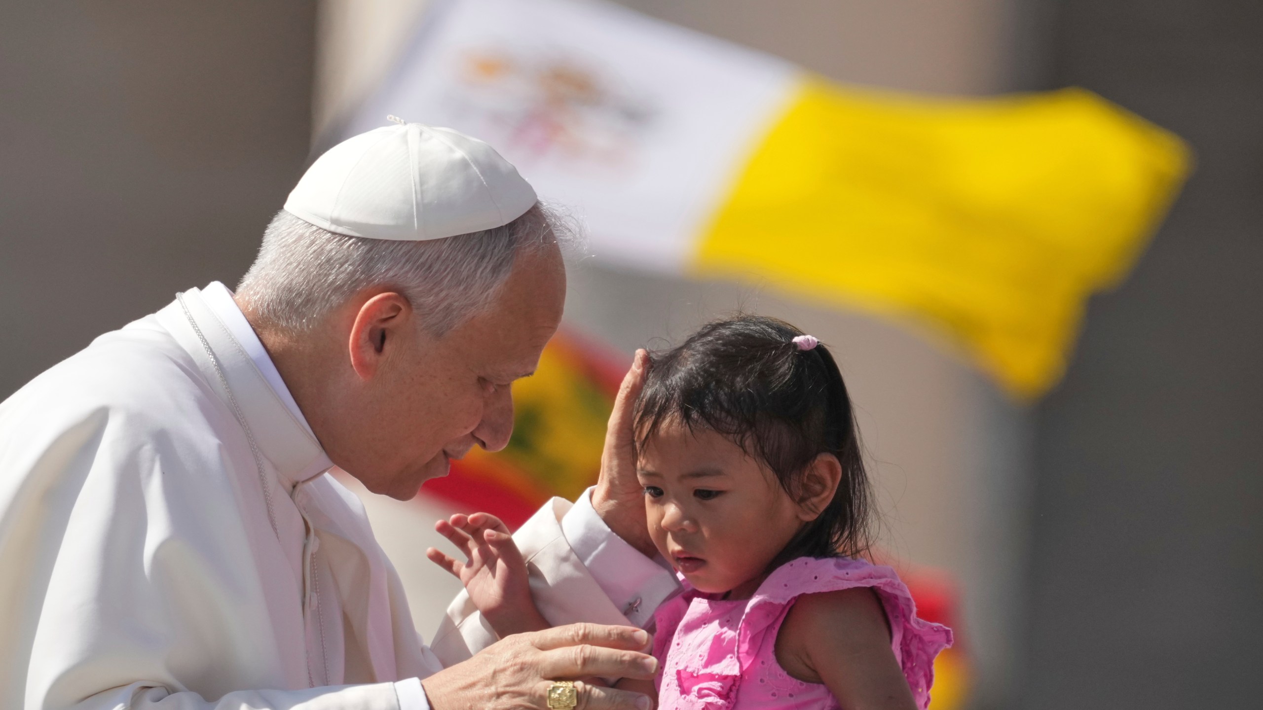 Pope Leo XIV caresses a little girl as he arrives to celebrate a Mass for the Jubilee of New Religious Associations on Pentecost Day in St. Peter's Square at the Vatican, Sunday, June 8, 2025. (AP Photo/Andrew Medichini)