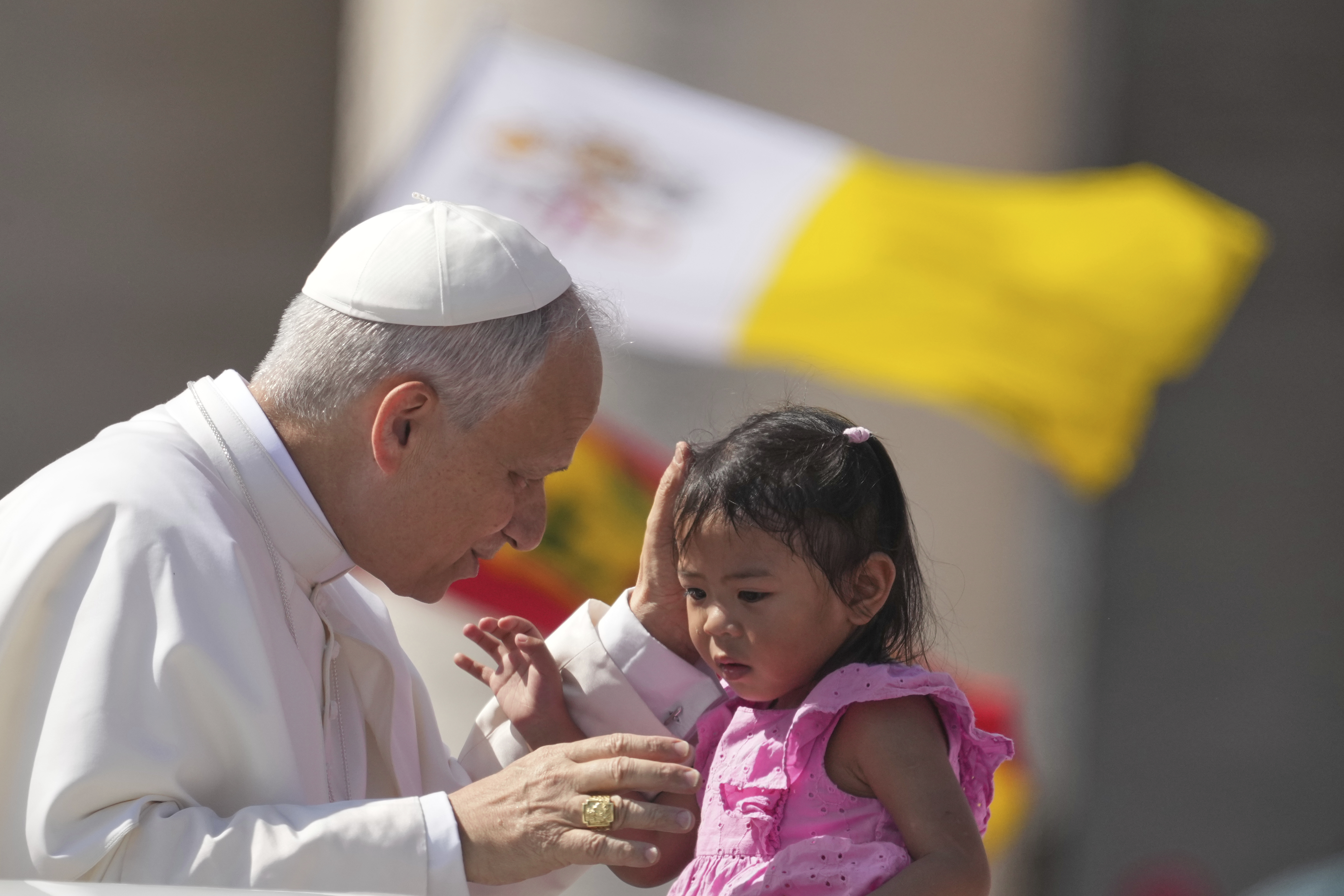 Pope Leo XIV caresses a little girl as he arrives to celebrate a Mass for the Jubilee of New Religious Associations on Pentecost Day in St. Peter's Square at the Vatican, Sunday, June 8, 2025. (AP Photo/Andrew Medichini)