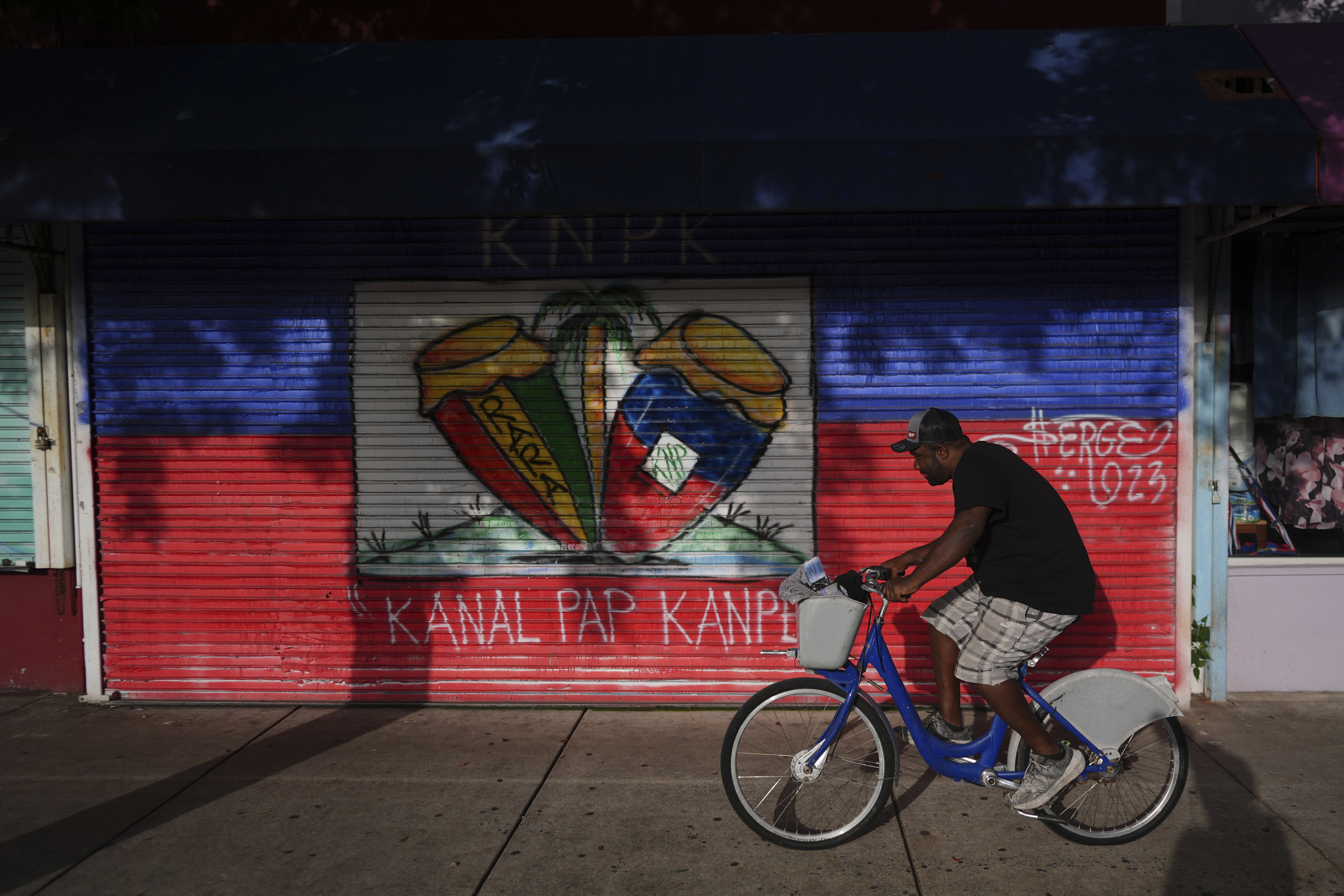 A man rides a bike past shops in Miami's Little Haiti neighborhood, Friday, June 6, 2025. (AP Photo/Rebecca Blackwell)