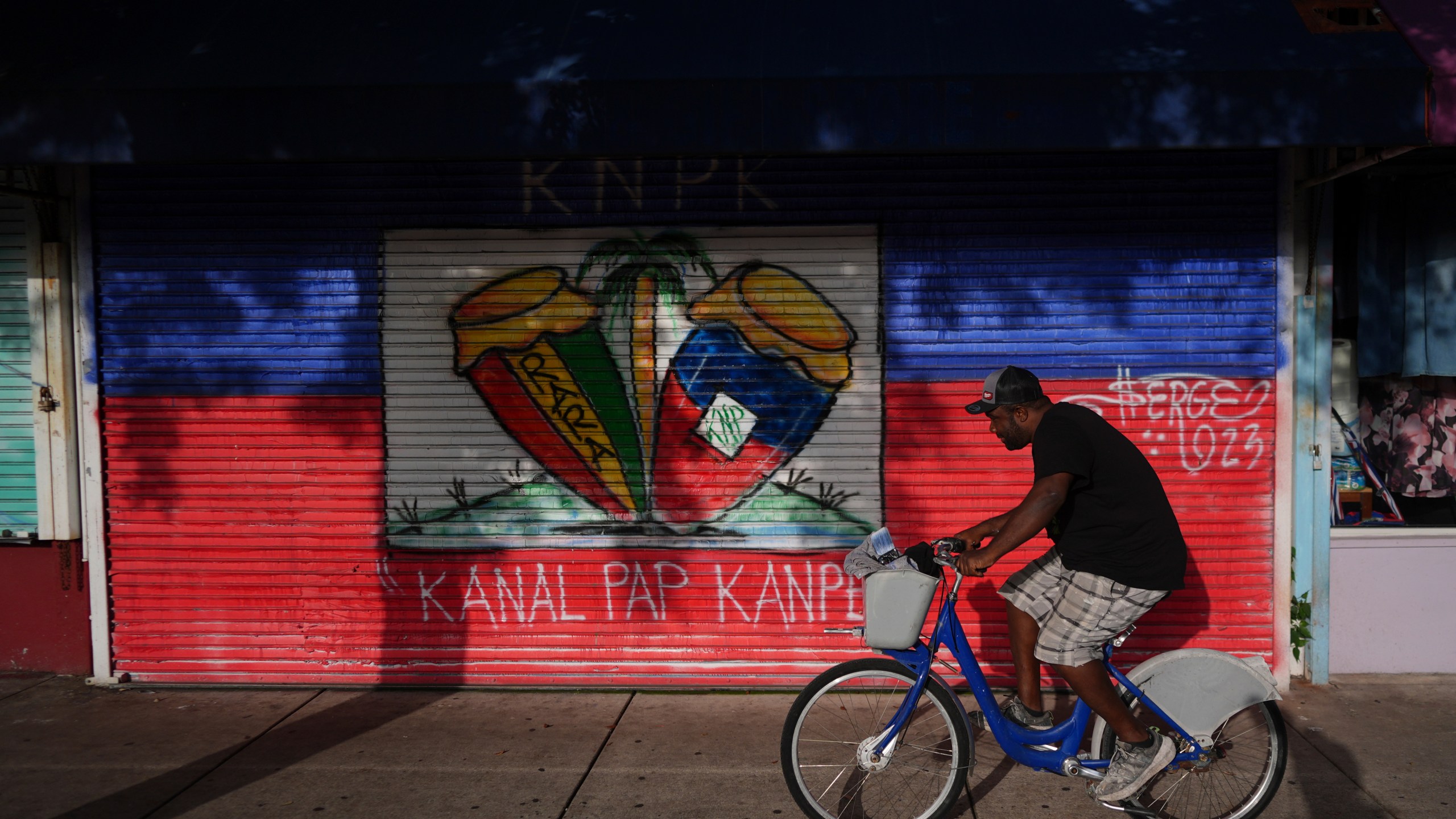 A man rides a bike past shops in Miami's Little Haiti neighborhood, Friday, June 6, 2025. (AP Photo/Rebecca Blackwell)