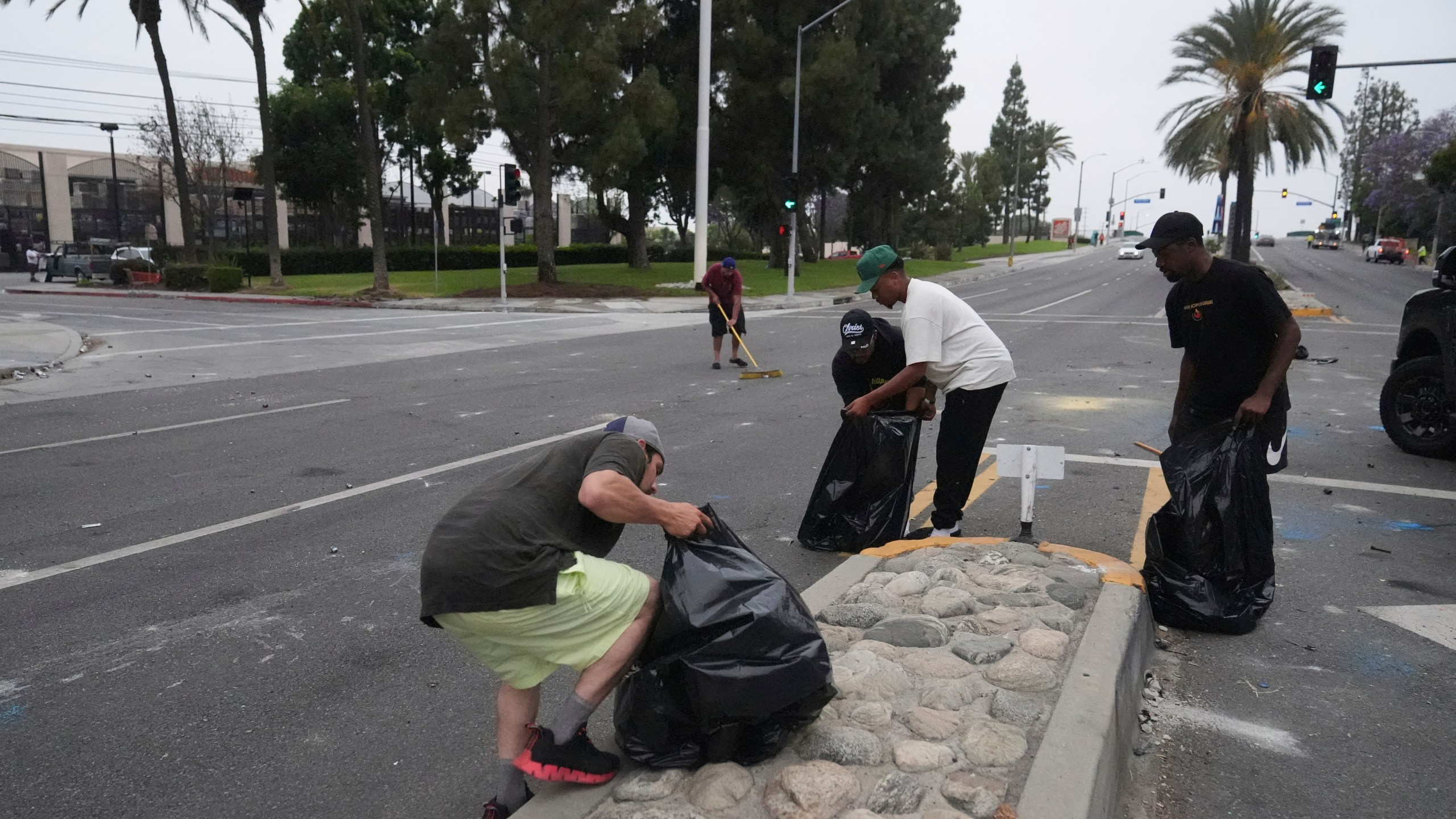 A local parishioners clean up the streets Sunday, June 8, 2025, in Paramount, Calif., following an immigration raid protest the night before. (AP Photo/Jae Hong)