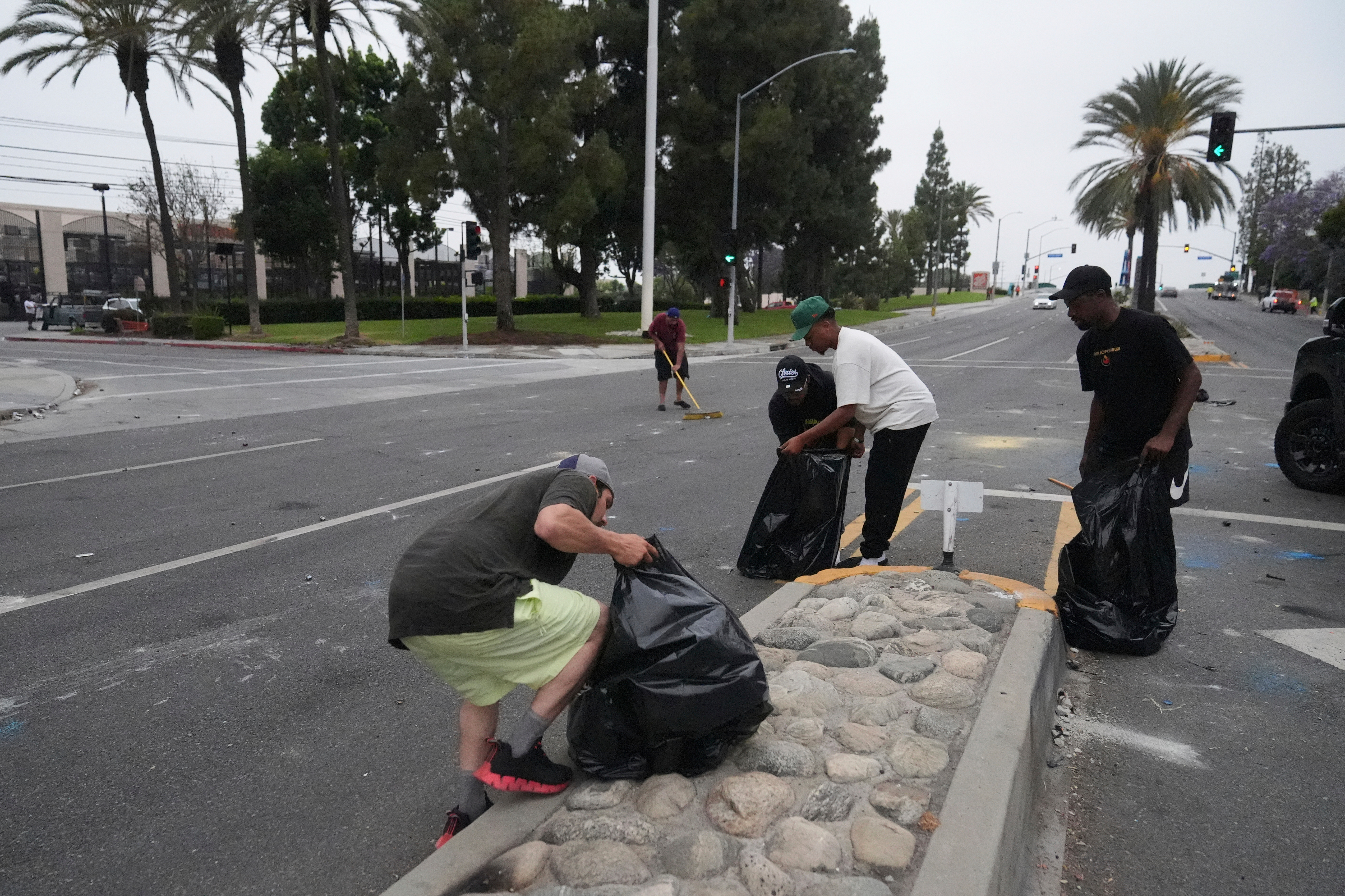 A local parishioners clean up the streets Sunday, June 8, 2025, in Paramount, Calif., following an immigration raid protest the night before. (AP Photo/Jae Hong)