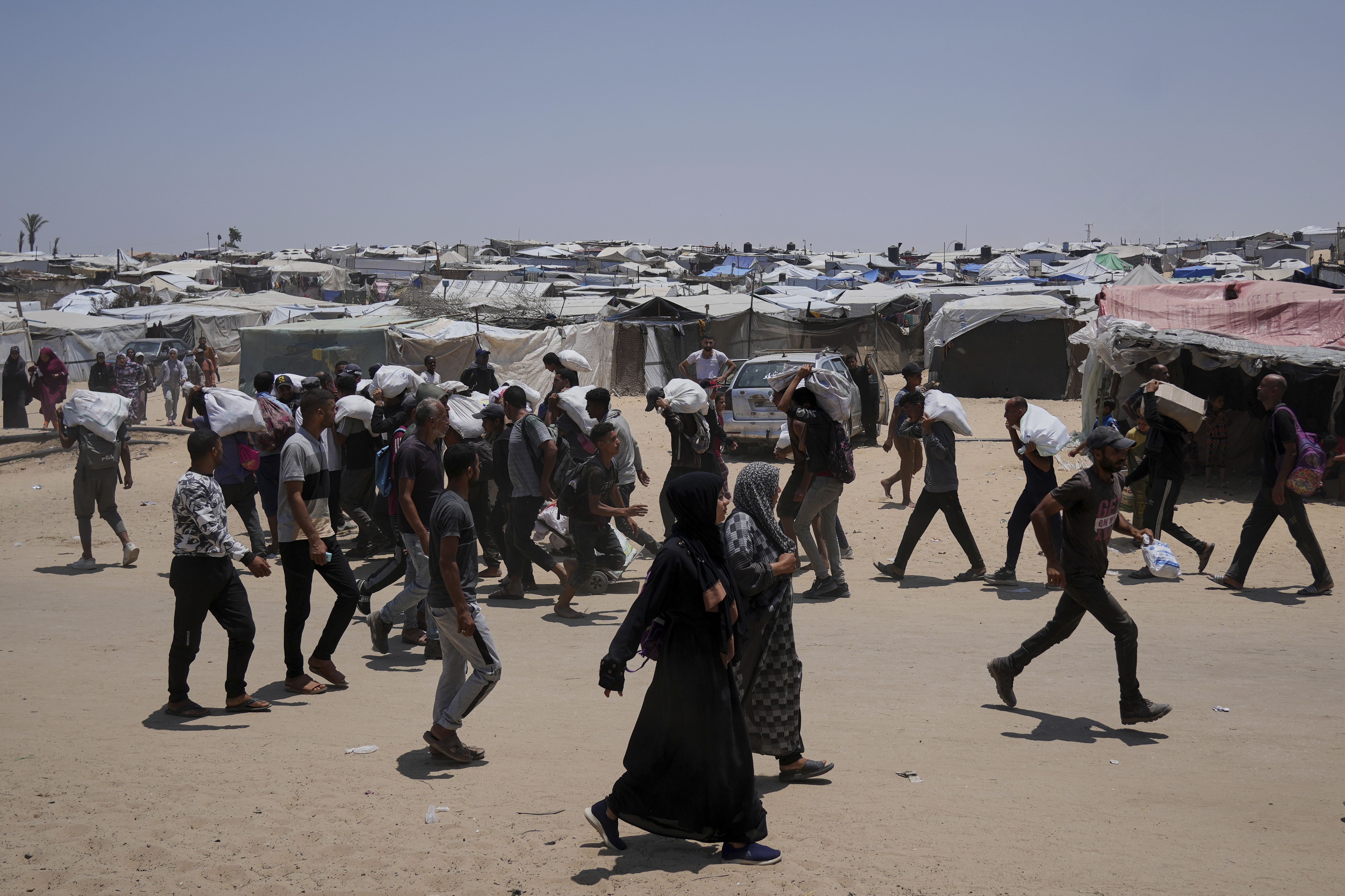 Palestinians carry bags containing food and humanitarian aid packages delivered by the Gaza Humanitarian Foundation, a U.S.-backed organization, in Rafah, southern Gaza Strip, Sunday, June 8, 2025. (AP Photo/Abdel Kareem Hana)