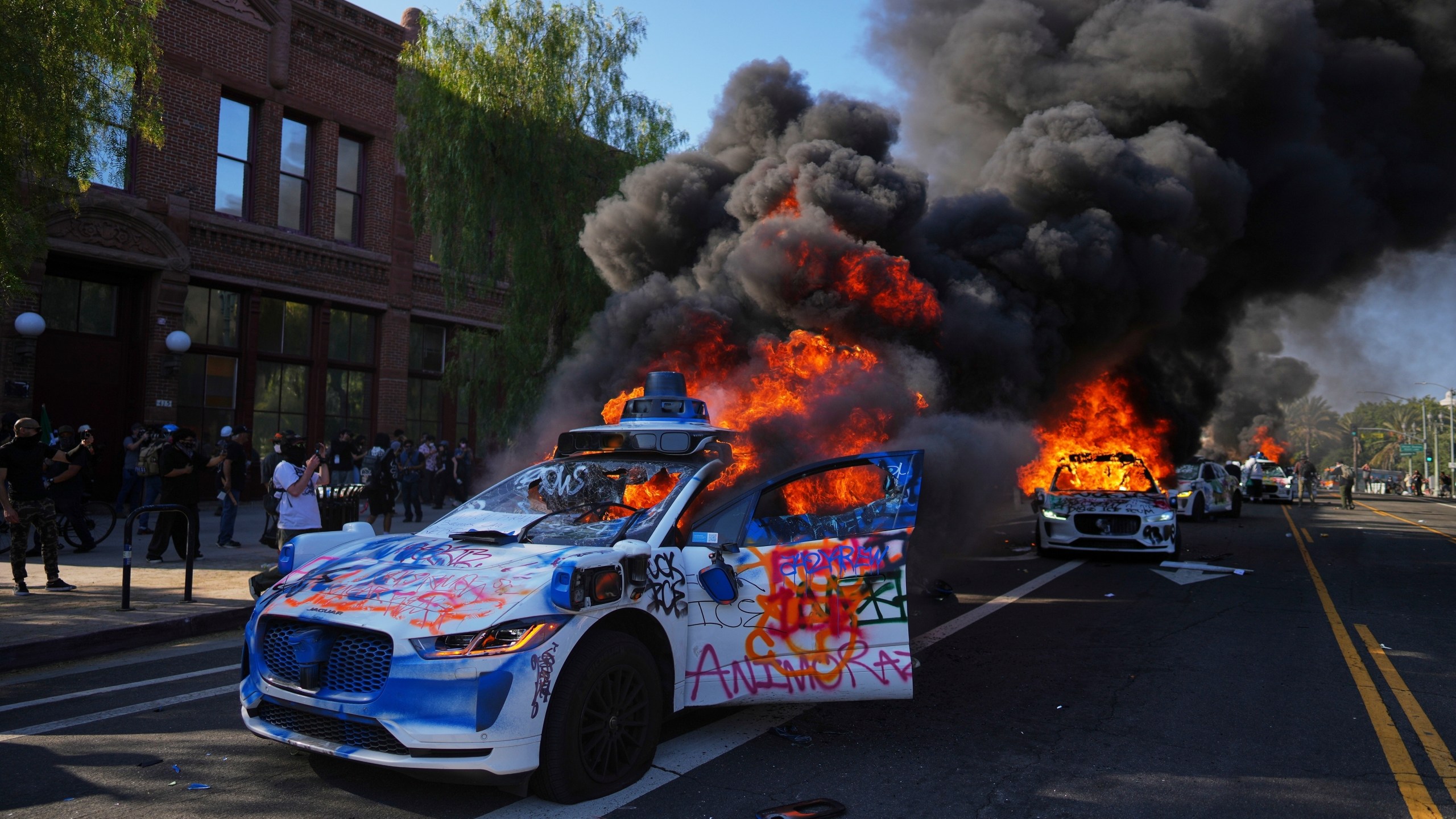 Multiple Waymo taxis burn near the Metropolitan Detention Center of downtown Los Angeles, Sunday, June 8, 2025, following last night's immigration raid protest. (AP Photo/Eric Thayer)