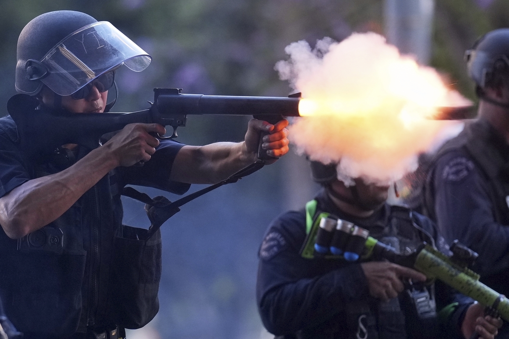 A police officer fires a soft round near the metropolitan detention center of downtown Los Angeles, Sunday, June 8, 2025, following last night's immigration raid protest. (AP Photo/Eric Thayer)