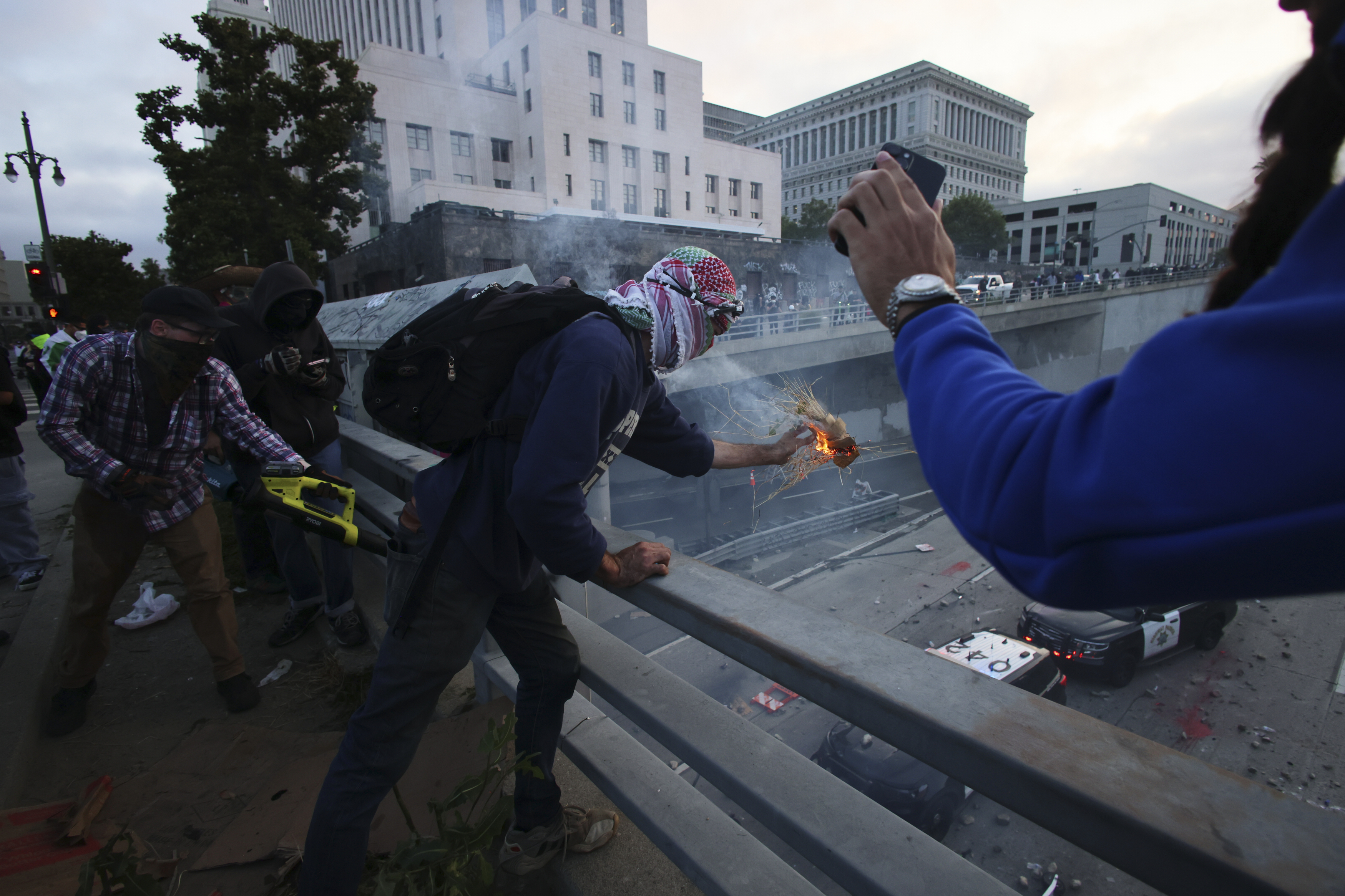 Protesters throw objects to the police vehicles on a Freeway near the Metropolitan Detention Center in downtown Los Angeles, Sunday, June 8, 2025. (AP Photo/Ethan Swope)