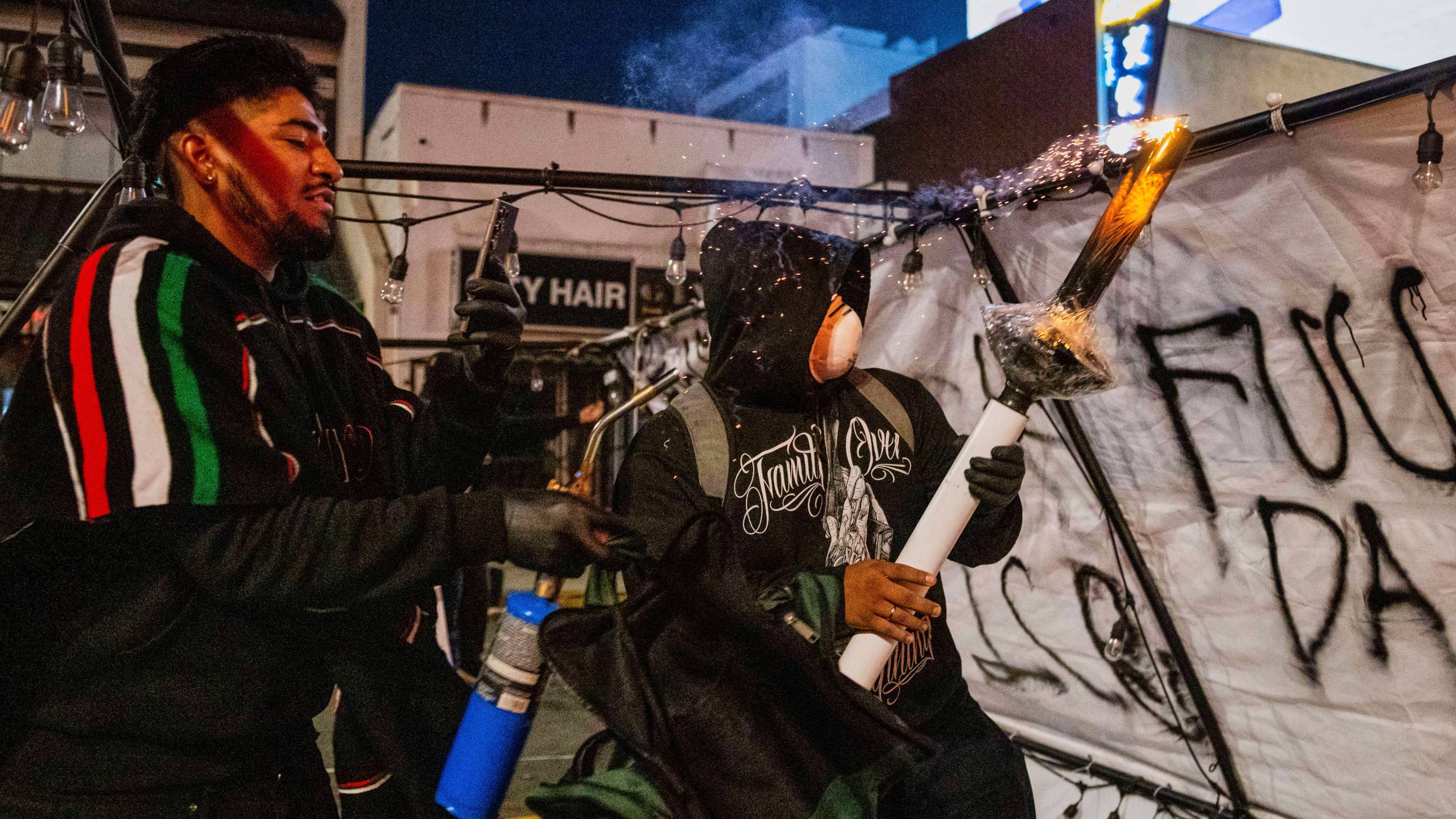 Protesters prepare to launch projectiles during protests over the Trump administration's immigration raids in Los Angeles, Monday, June 9, 2025. (AP Photo/Ethan Swope)