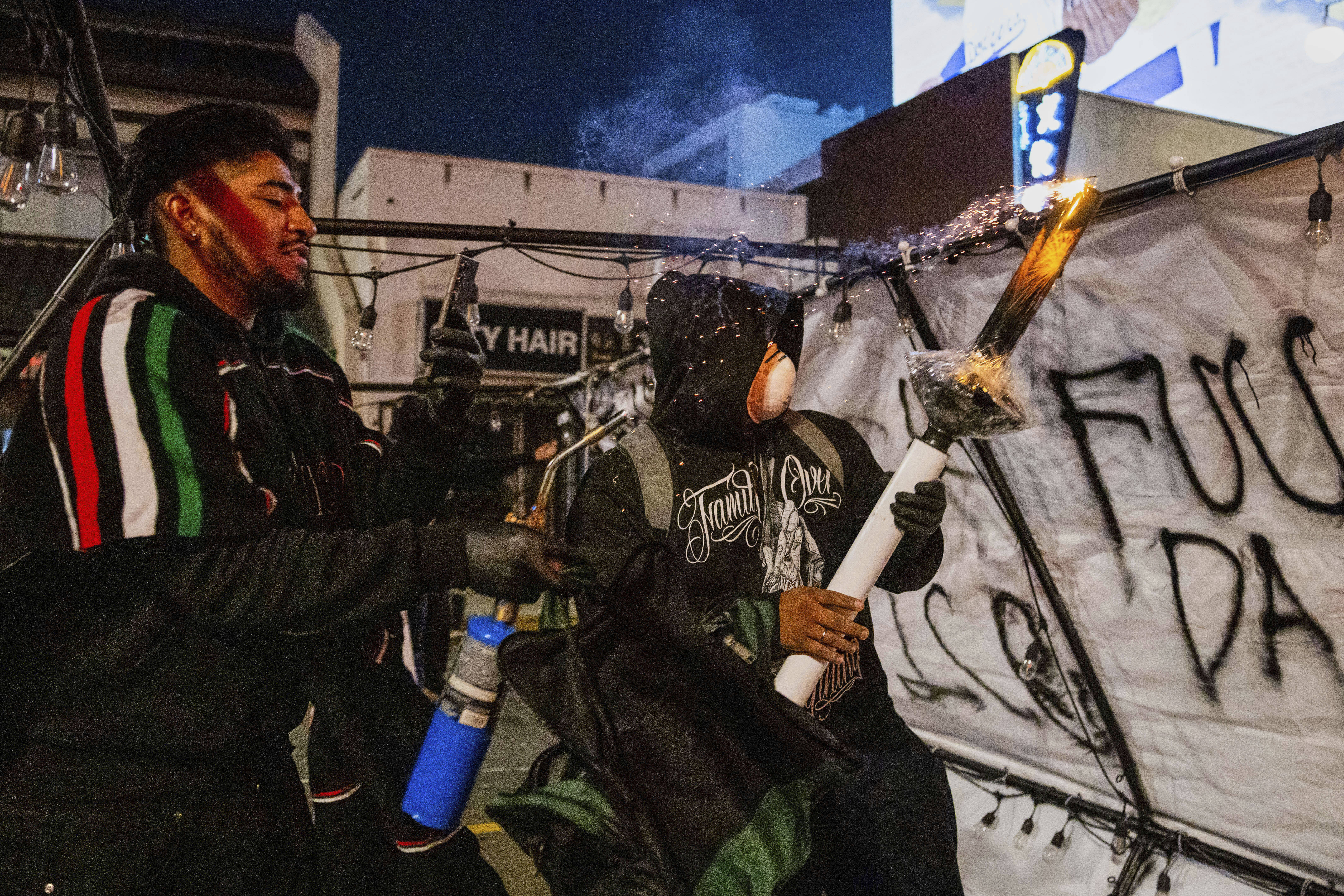 Protesters prepare to launch projectiles during protests over the Trump administration's immigration raids in Los Angeles, Monday, June 9, 2025. (AP Photo/Ethan Swope)