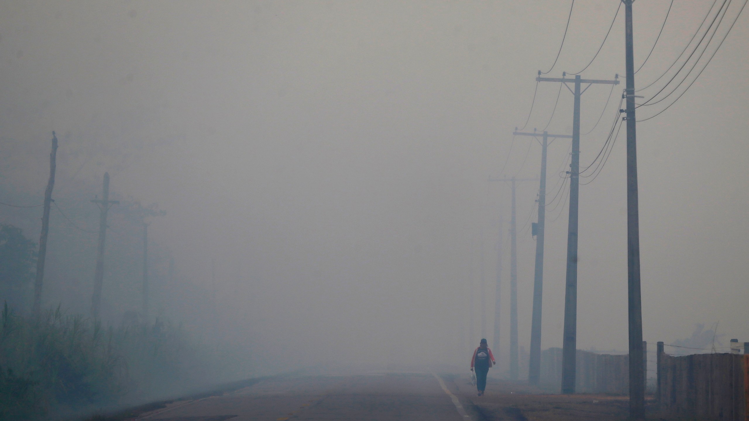 FILE - A person walks on the BR-319 highway through smoke from a forest fire that reaches Careiro Castanho in Brazil's Amazonas state, Sept. 6, 2023. (AP Photo/Edmar Barros, File)