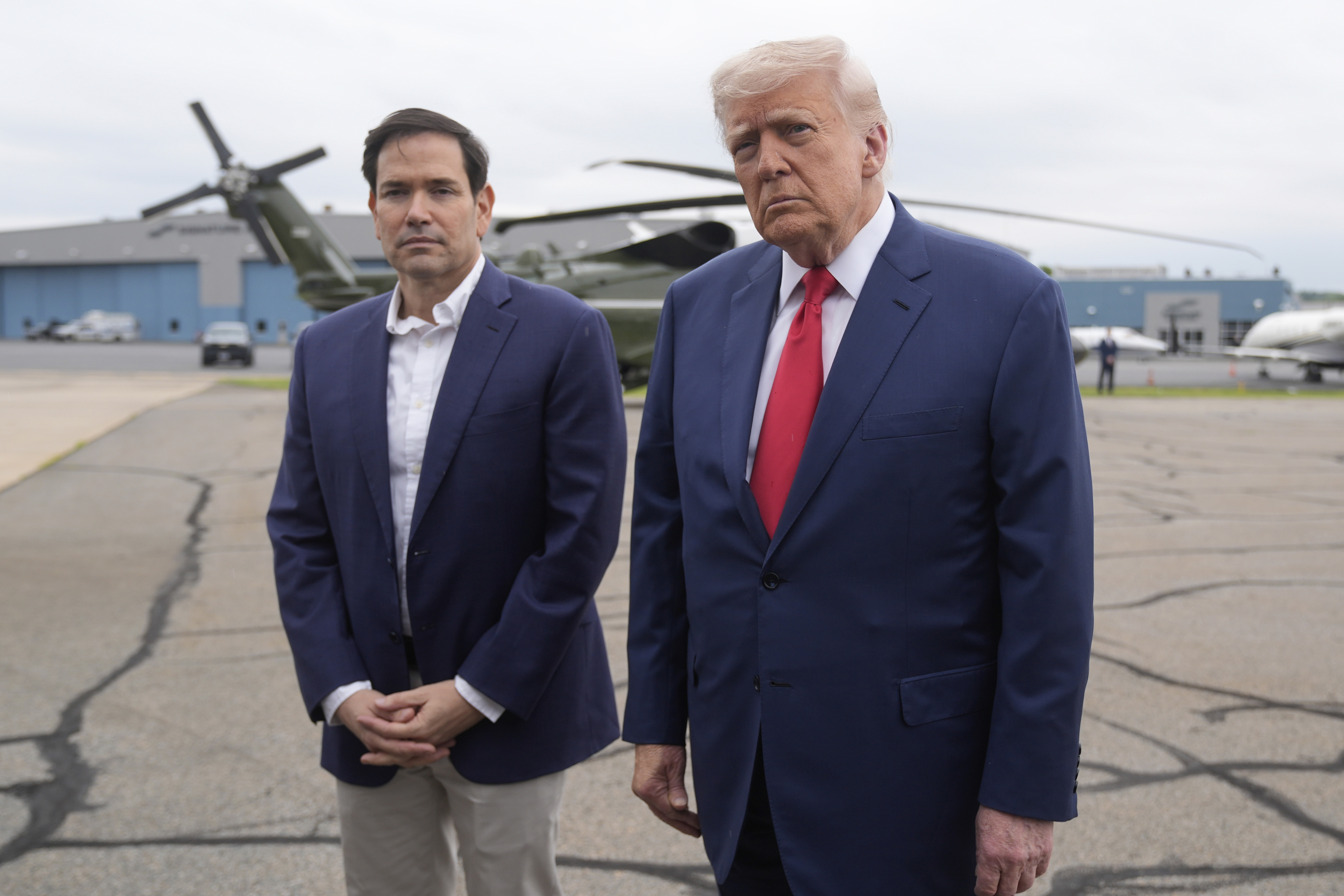 President Donald Trump, right, listens to a question from a reporter alongside Secretary of State Marco Rubio upon arriving at Morristown Municipal Airport in Morristown, N.J., en route to Camp David, Md., Sunday, June 8, 2025. (AP Photo/Manuel Balce Ceneta)