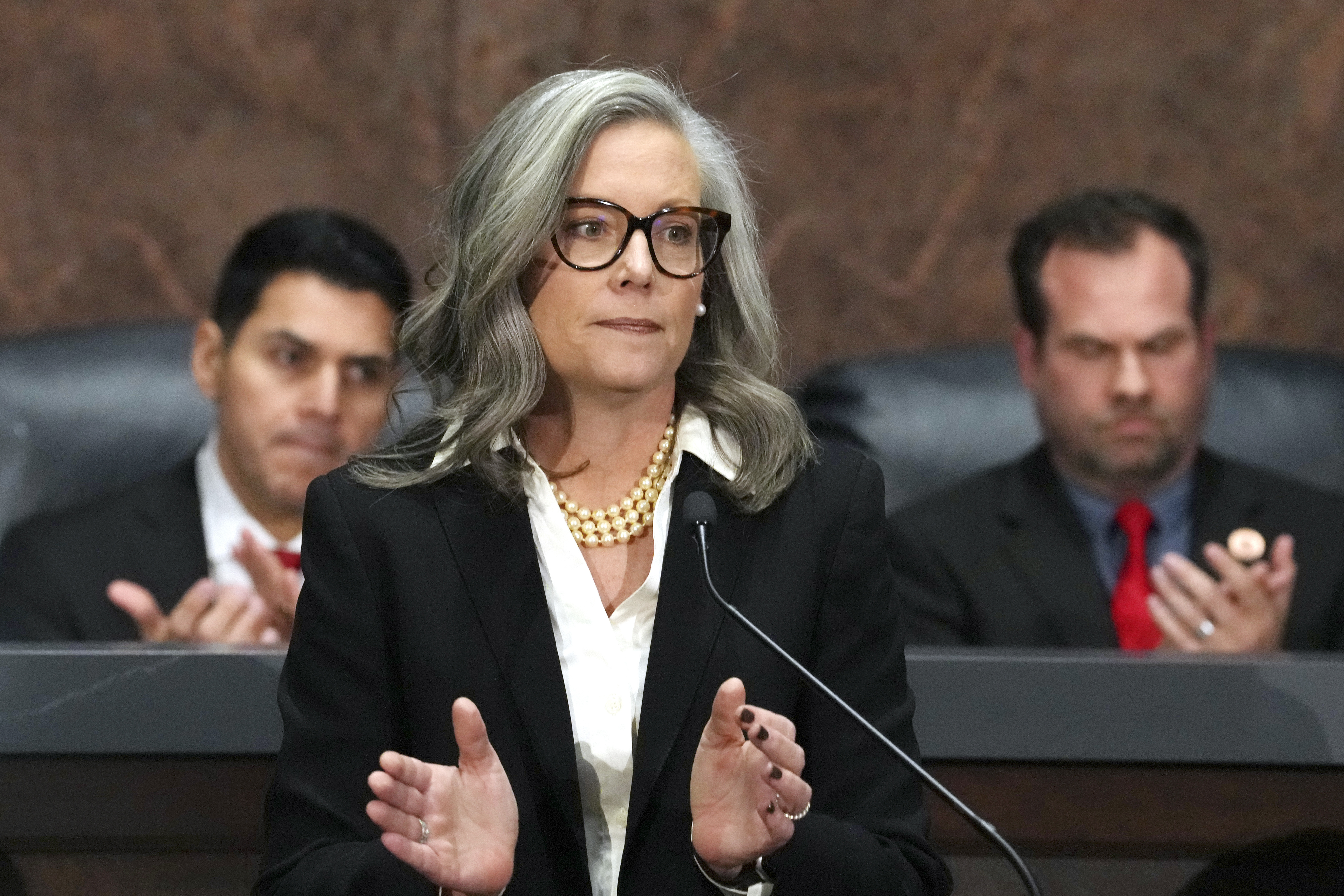 FILE - Arizona Democratic Gov. Katie Hobbs, center, applauds for those affected by the Los Angeles area wildfires as she gives the State of the State address in the House of Representatives at the state Capitol with Speaker of the House Rep. Steve Montenegro, R-Litchfield Park, left, and Senate President Warren Petersen, R-Gilbert, flanking the governor on Jan. 13, 2025, in Phoenix. (AP Photo/Ross D. Franklin, File)