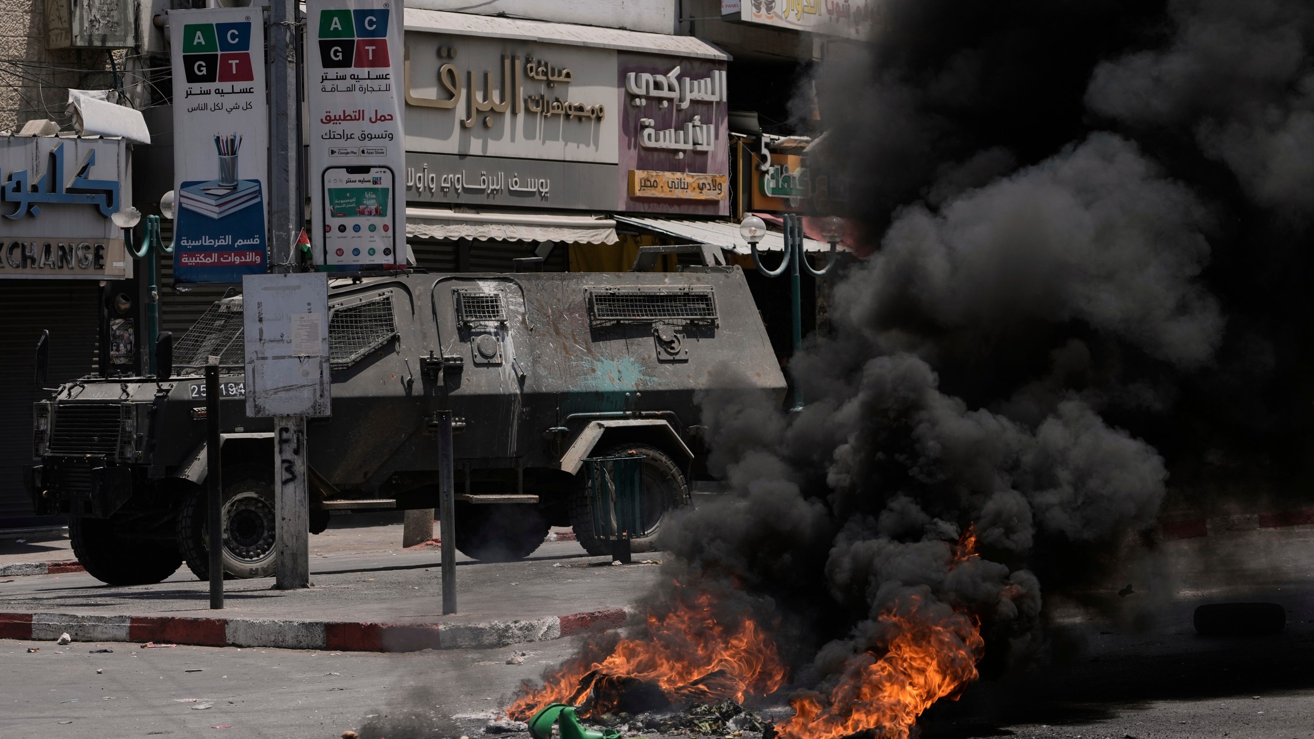 An Israeli armoured vehicle drives near burning tires during a military raid in the West Bank city of Nablus, Tuesday, June 10, 2025. (AP Photo/Majdi Mohammed)
