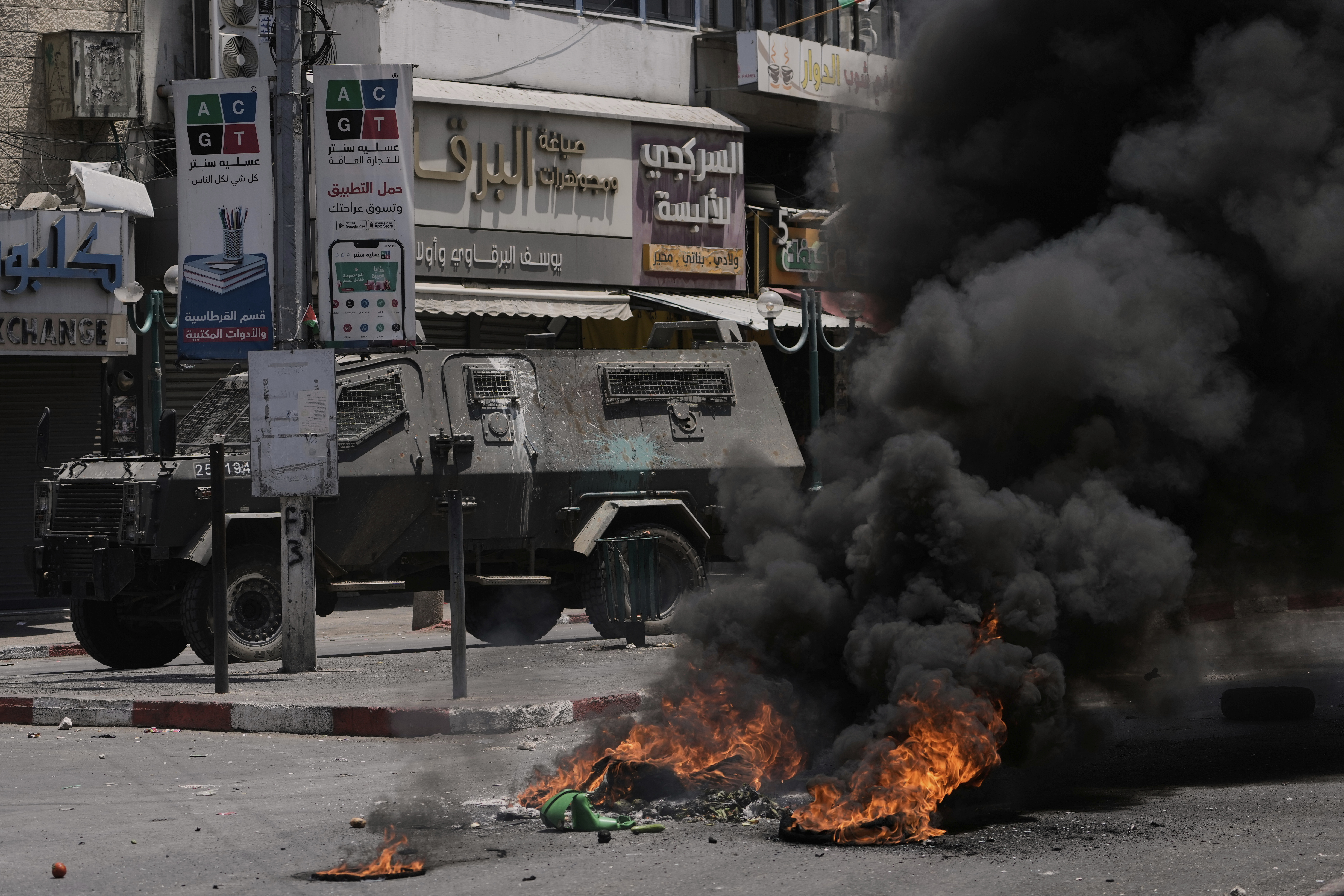 An Israeli armoured vehicle drives near burning tires during a military raid in the West Bank city of Nablus, Tuesday, June 10, 2025. (AP Photo/Majdi Mohammed)