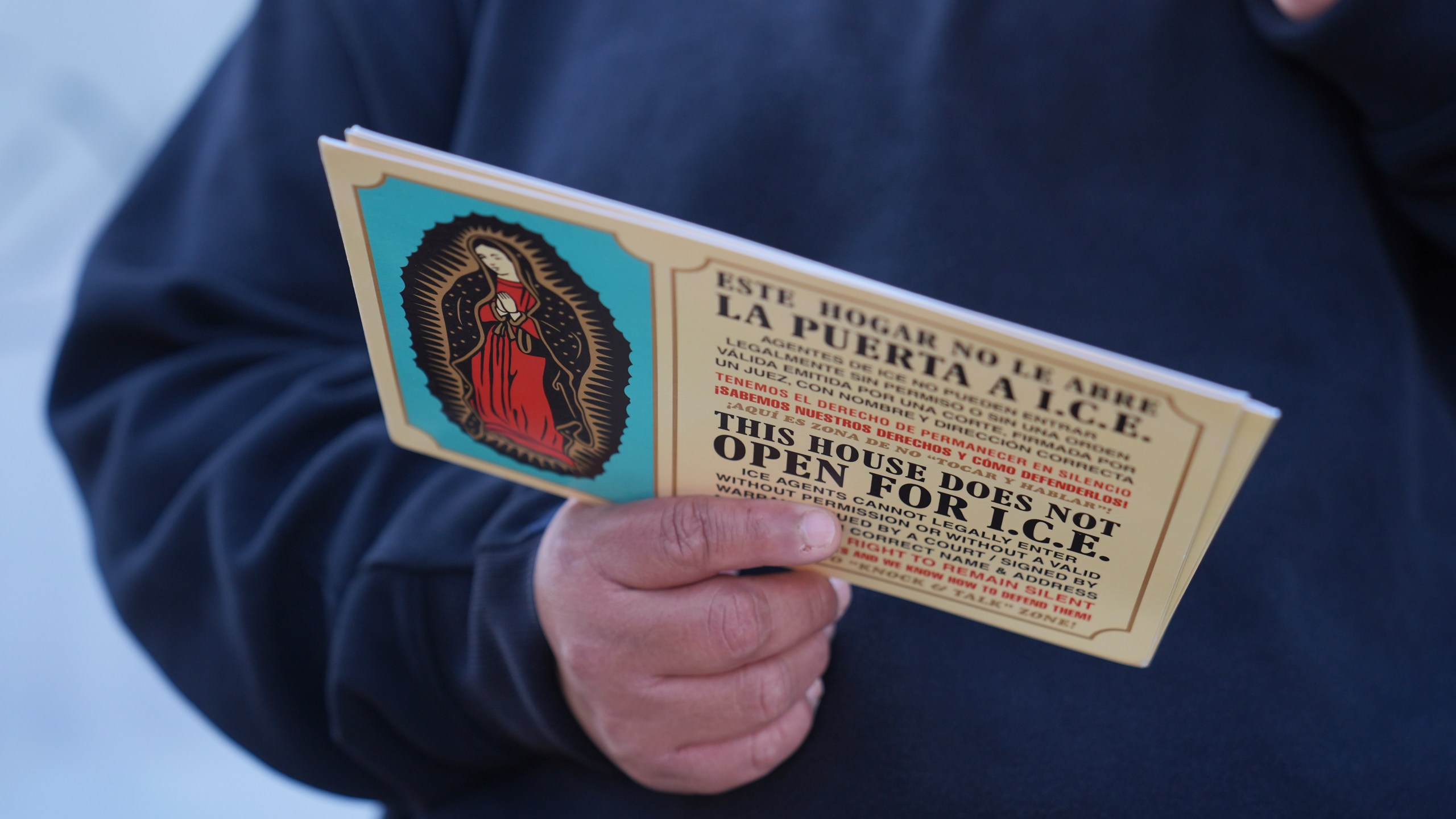 FILE - A woman outside Ambiance Apparel holds a card about Immigration and Customs Enforcement after authorities conducted an operation, Friday, June 6, 2025, in Los Angeles. (AP Photo/Jae C. Hong, File)