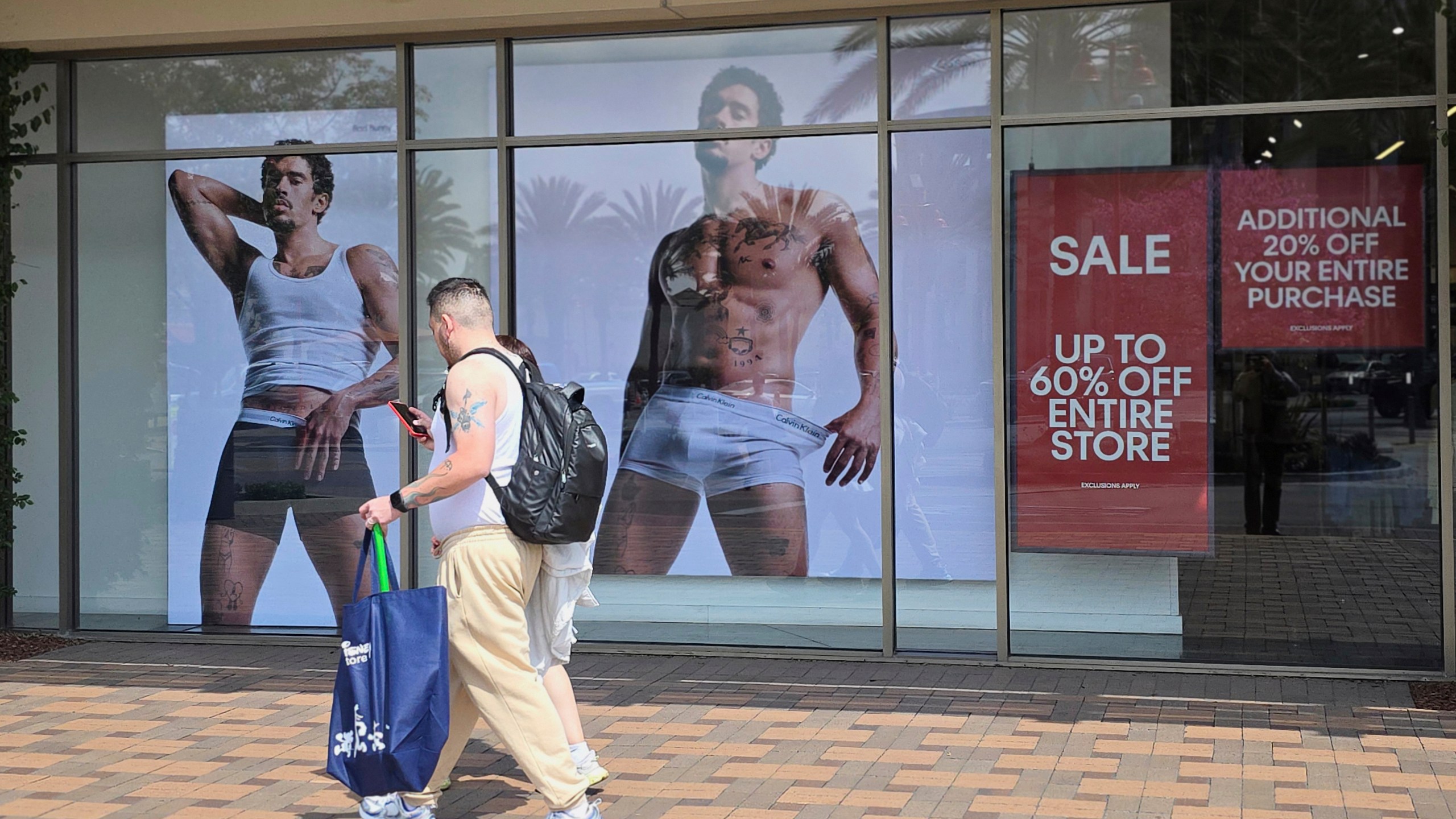 FILE - Shoppers walks past a Calvin Klein store at Citadel Outlets in Commerce, Calif., April 14, 2025. (AP PhotoDamian Dovarganes, file)