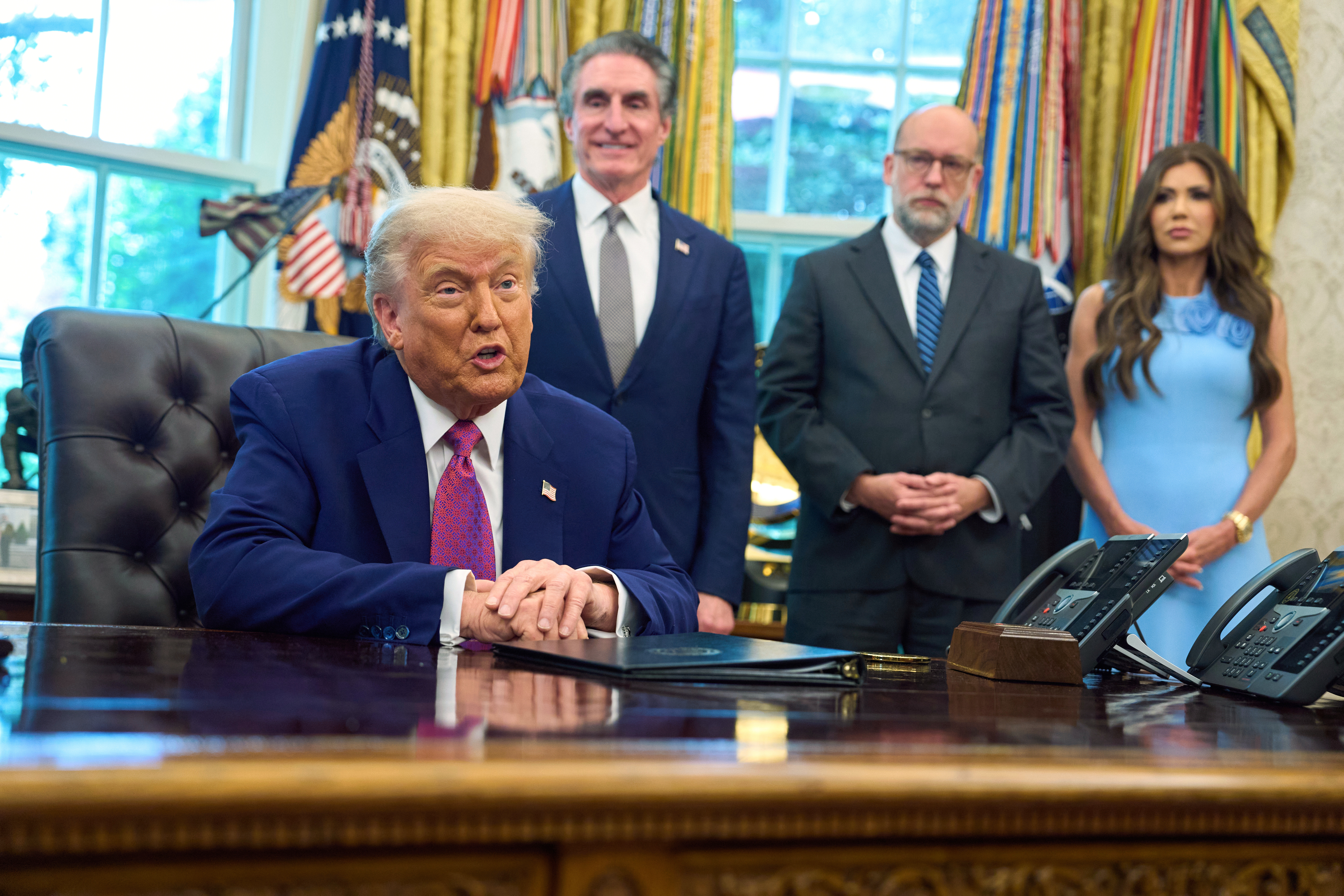 President Donald Trump speaks with reporters in the Oval Office of the the White House, Tuesday, June 10, 2025, in Washington, as from left, Interior Secretary Doug Burgum, Office of Management and Budget Director Russell Vought, and Homeland Security Secretary Kristi Noem, listen. (AP Photo/Evan Vucci)