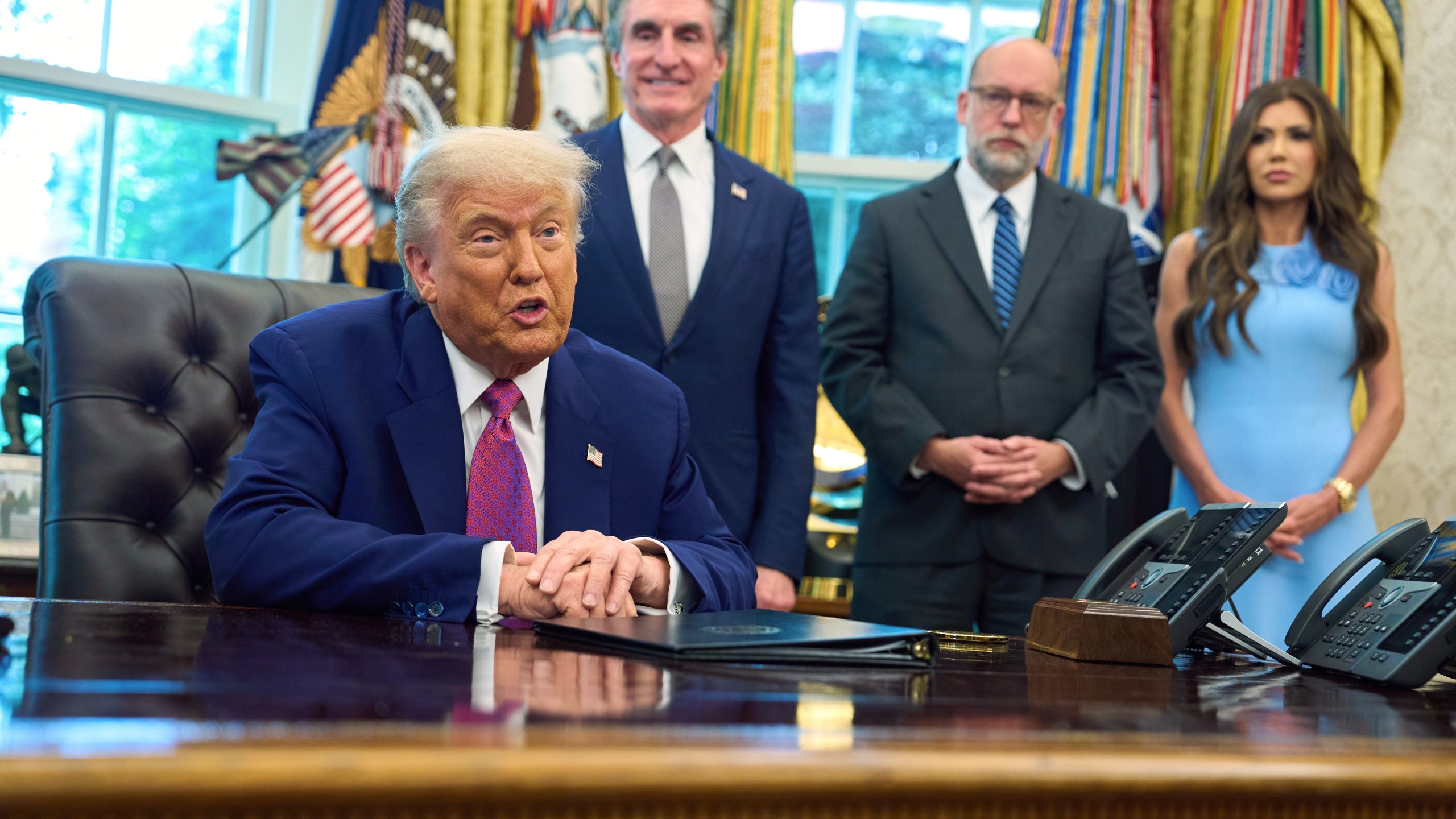 President Donald Trump speaks with reporters in the Oval Office of the the White House, Tuesday, June 10, 2025, in Washington, as from left, Interior Secretary Doug Burgum, Office of Management and Budget Director Russell Vought, and Homeland Security Secretary Kristi Noem, listen. (AP Photo/Evan Vucci)