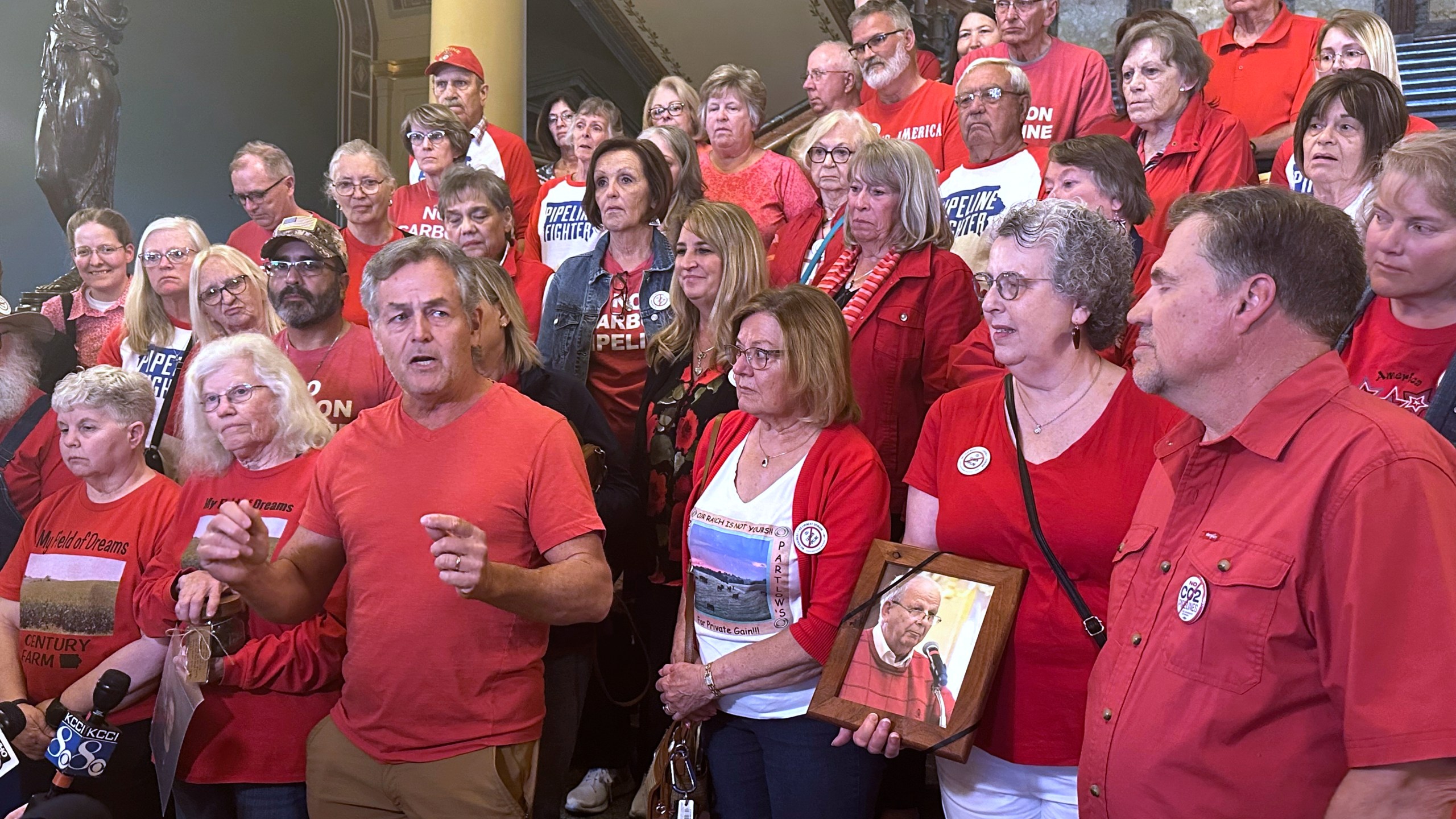 Iowans in red shirts speak to reporters at the statehouse in Des Moines, Iowa, Friday, May 9, 2025 to reiterate their opposition to a massive carbon-capture pipeline project routed across several Midwest states. (AP Photo/Hannah Fingerhut)