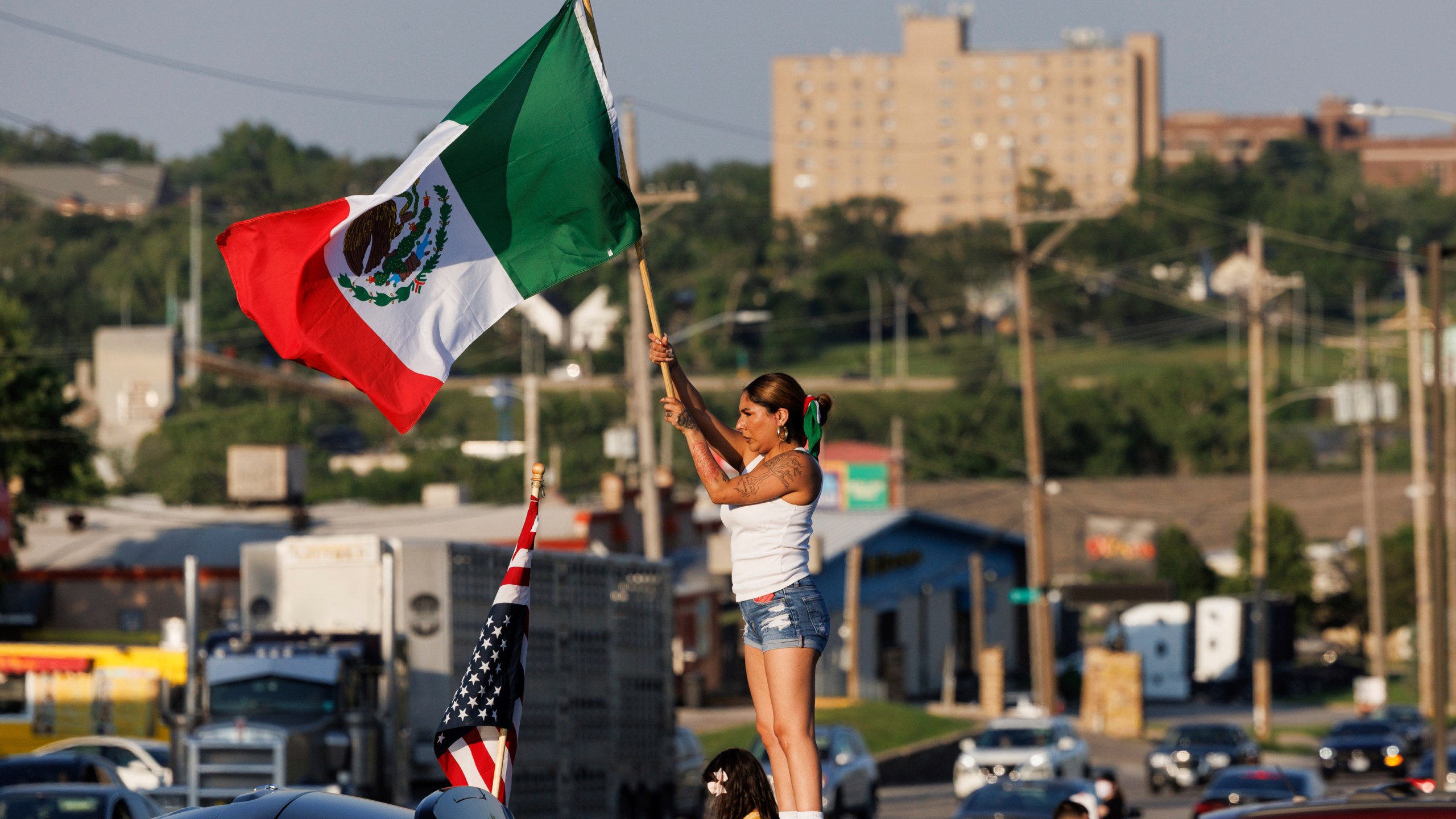 Brila Adauto of Omaha waves a Mexican flag as hundreds gather in after U.S. Immigration and Customs Enforcement conducted a raid earlier in the day in Omaha, Neb. on Tuesday, June 10, 2025. (Nikos Frazier/Omaha World-Herald via AP)