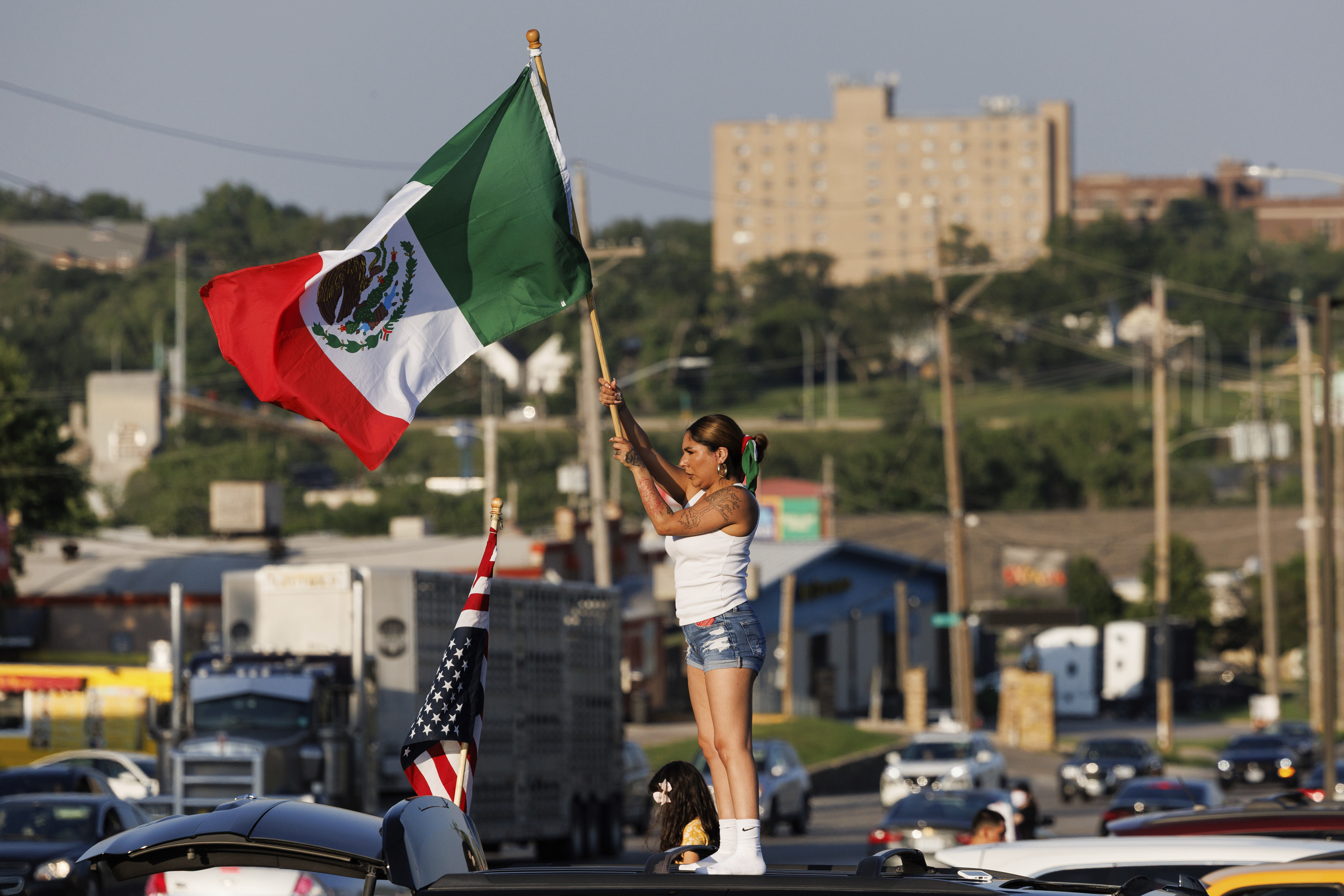Brila Adauto of Omaha waves a Mexican flag as hundreds gather in after U.S. Immigration and Customs Enforcement conducted a raid earlier in the day in Omaha, Neb. on Tuesday, June 10, 2025. (Nikos Frazier/Omaha World-Herald via AP)