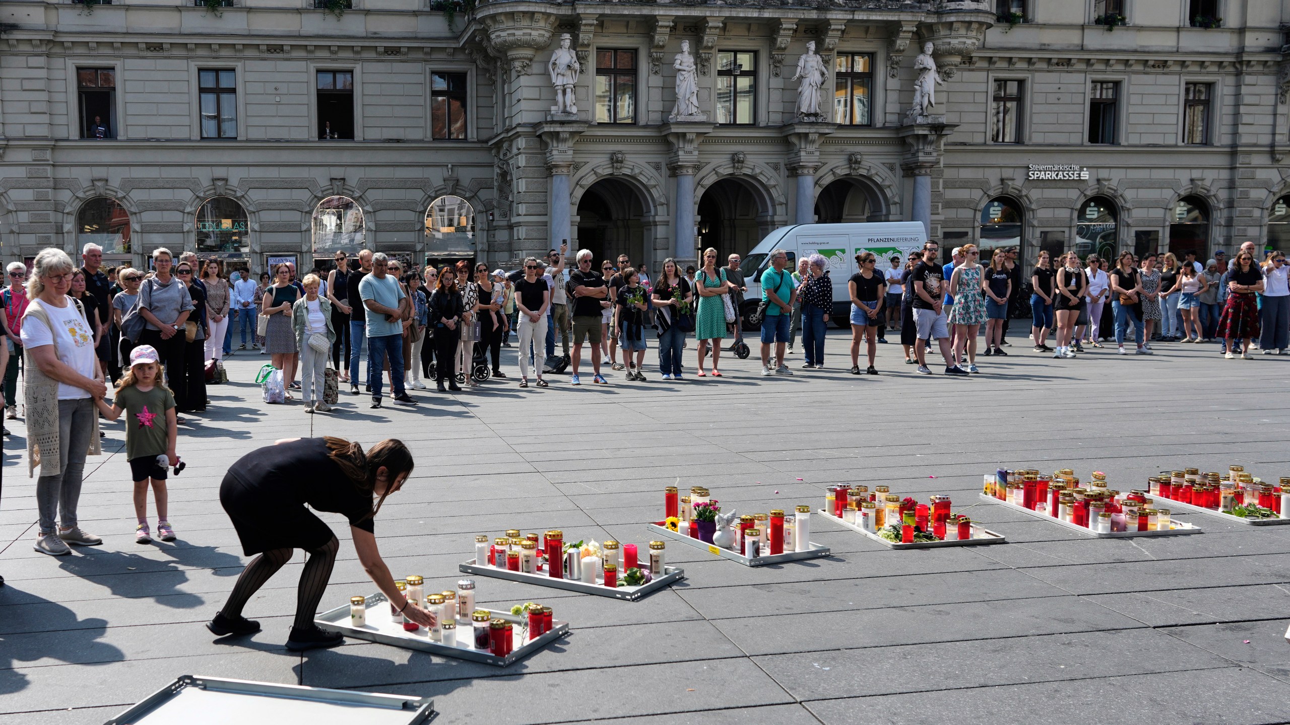 People pay a moment of silence on the main square after a former student opened fire the day before at a school fatally wounding several people and injuring many others before taking his own life, Graz, Austria, Wednesday, June 11, 2025. (AP Photo/Darko Bandic)