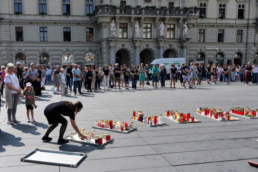 People pay a moment of silence on the main square after a former student opened fire the day before at a school fatally wounding several people and injuring many others before taking his own life, Graz, Austria, Wednesday, June 11, 2025. (AP Photo/Darko Bandic)