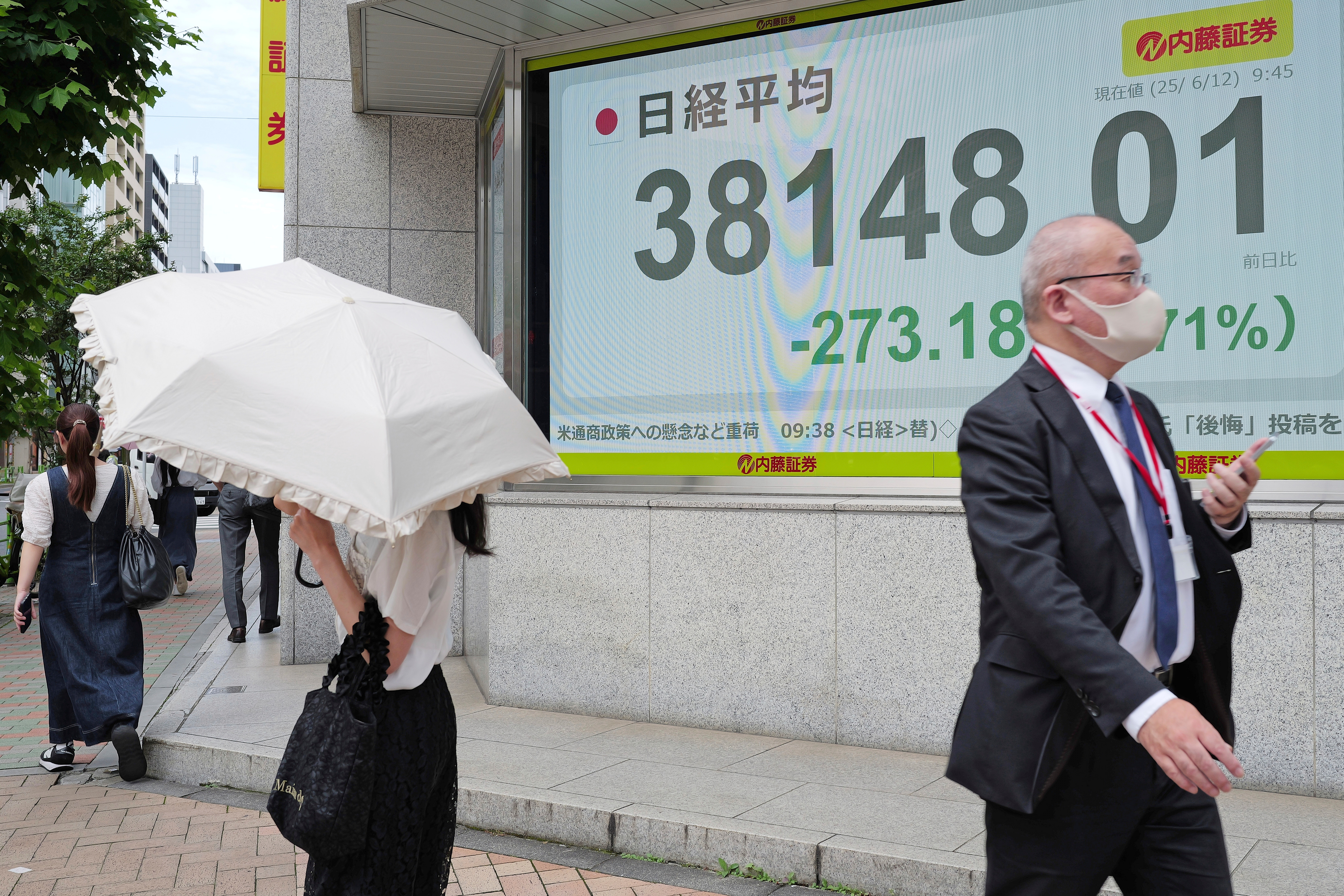 People walk in front of an electronic stock board showing Japan's Nikkei index at a securities firm Thursday, June 12, 2025, in Tokyo. (AP Photo/Eugene Hoshiko)