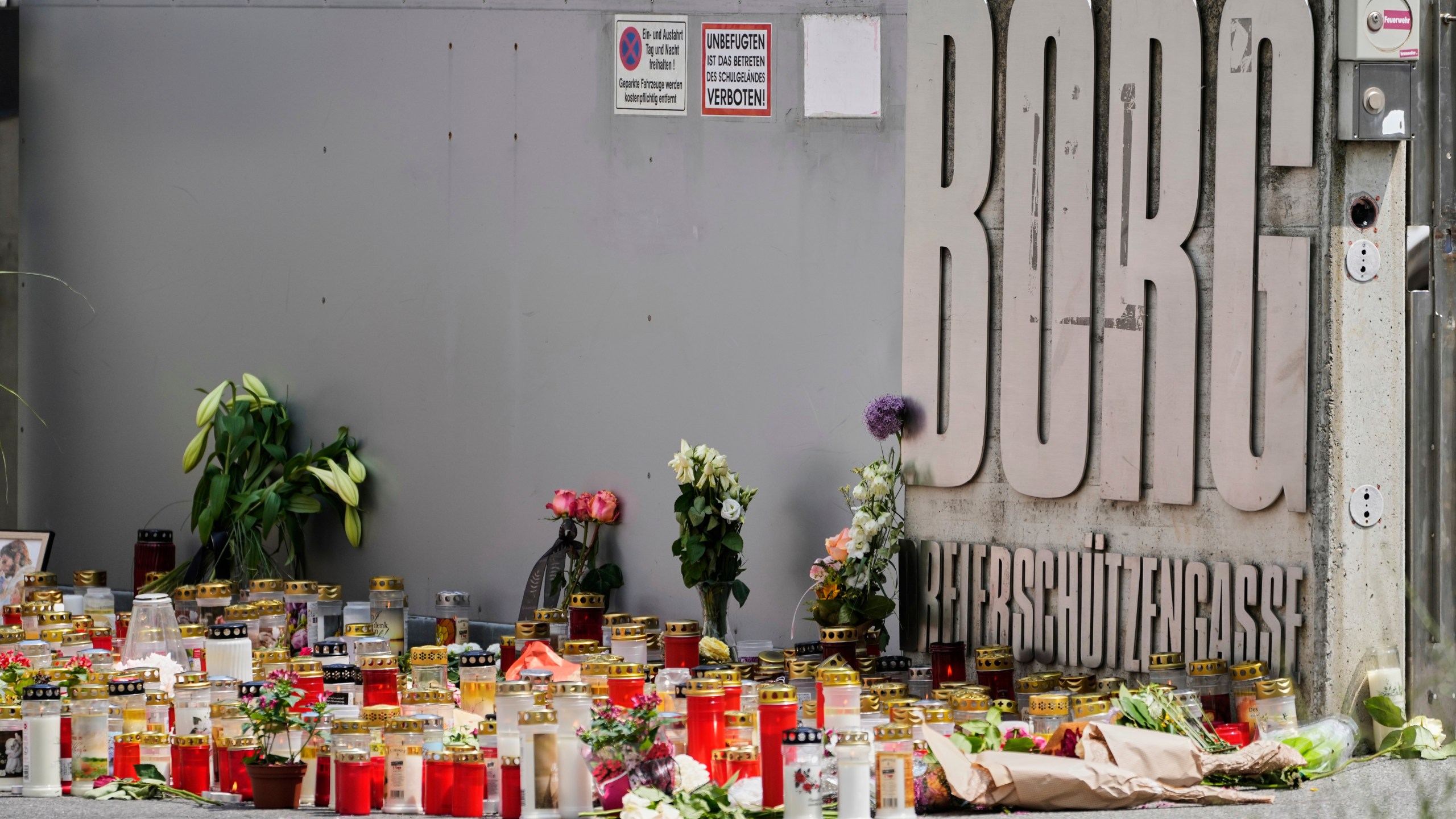 Flowers and candles are laid outside a school where a former student opened fire the day before fatally wounding several people and injuring many others before taking his own life, Graz, Austria, Wednesday, June 11, 2025. (AP Photo/Darko Bandic)