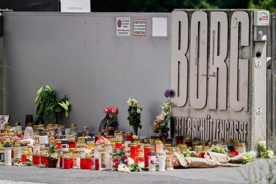 Flowers and candles are laid outside a school where a former student opened fire the day before fatally wounding several people and injuring many others before taking his own life, Graz, Austria, Wednesday, June 11, 2025. (AP Photo/Darko Bandic)