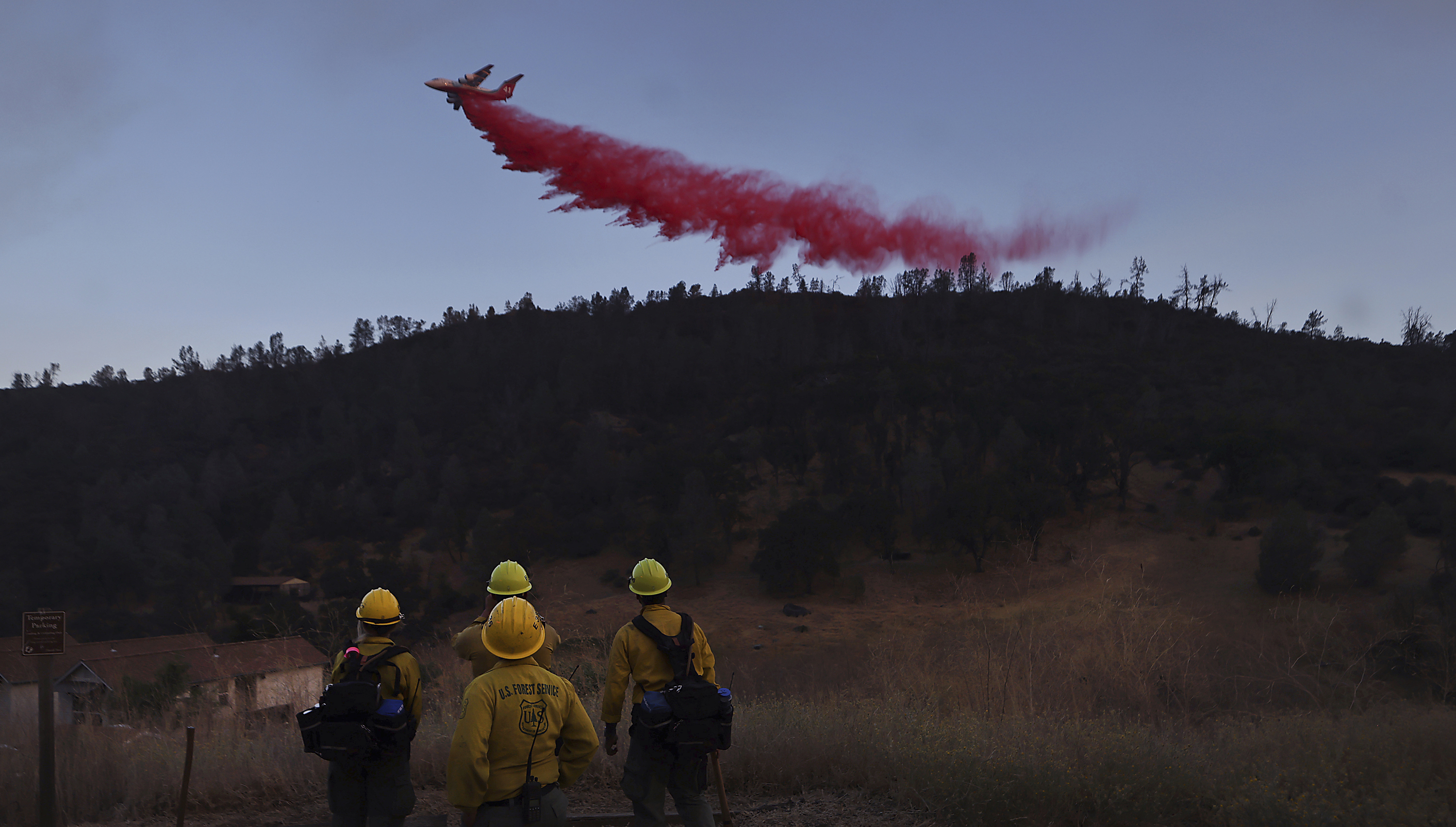 FILE - U,S. Forest Service firefighters from Stonyford, Calif., from left, Vivian Perez, Emma Nieforth, Jonny Connelly and Nick Bonnie watch as a BAe-146 air tanker is used to go indirect on the Ridge Fire, as a secondary contingency line, July 20, 2024, east of Clearlake, Calif. (Kent Porter/The Press Democrat via AP, File)