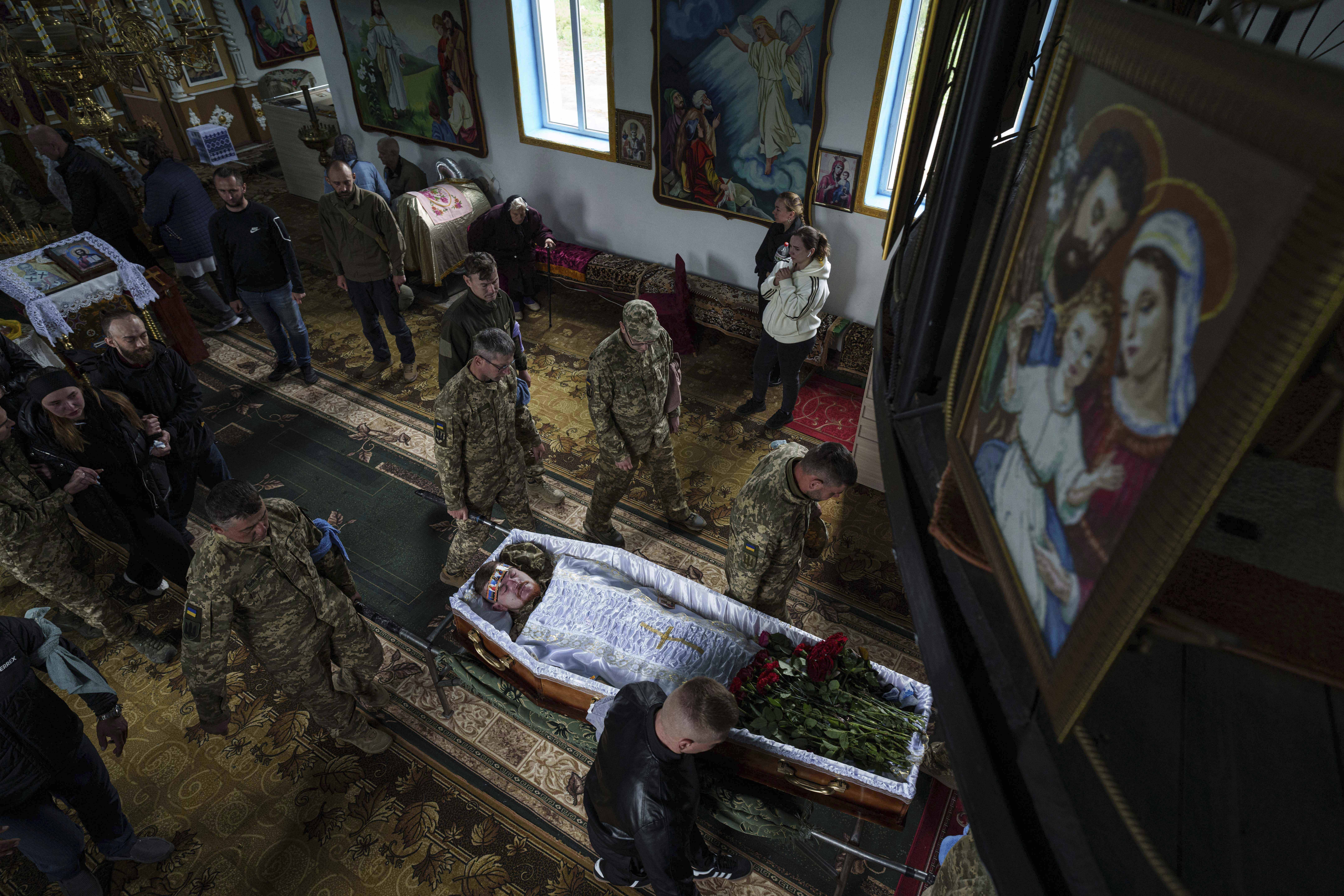 An honor guard carries the coffin of Dmytro Shapovalov, a Ukrainian serviceman, during his funeral ceremony at the church in Yosypivka village, Vinnytsia region, Ukraine, on Friday, June 13, 2025. (AP Photo/Evgeniy Maloletka)