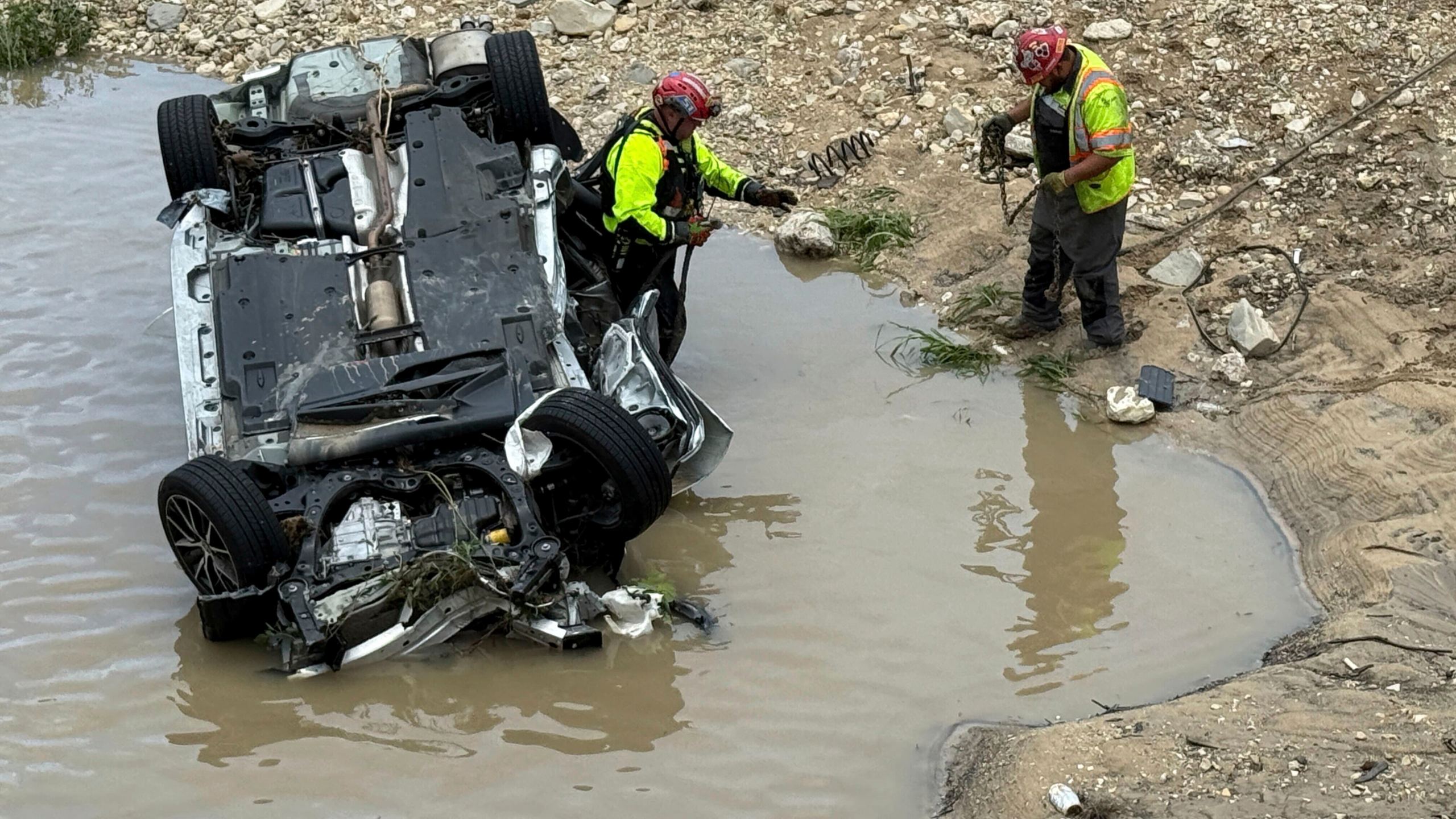 A crew works near a vehicle that was swept away in floodwaters in San Antonio, Texas, on Thursday, June 12, 2025. (AP Photo/Lekan Oyekanmi)