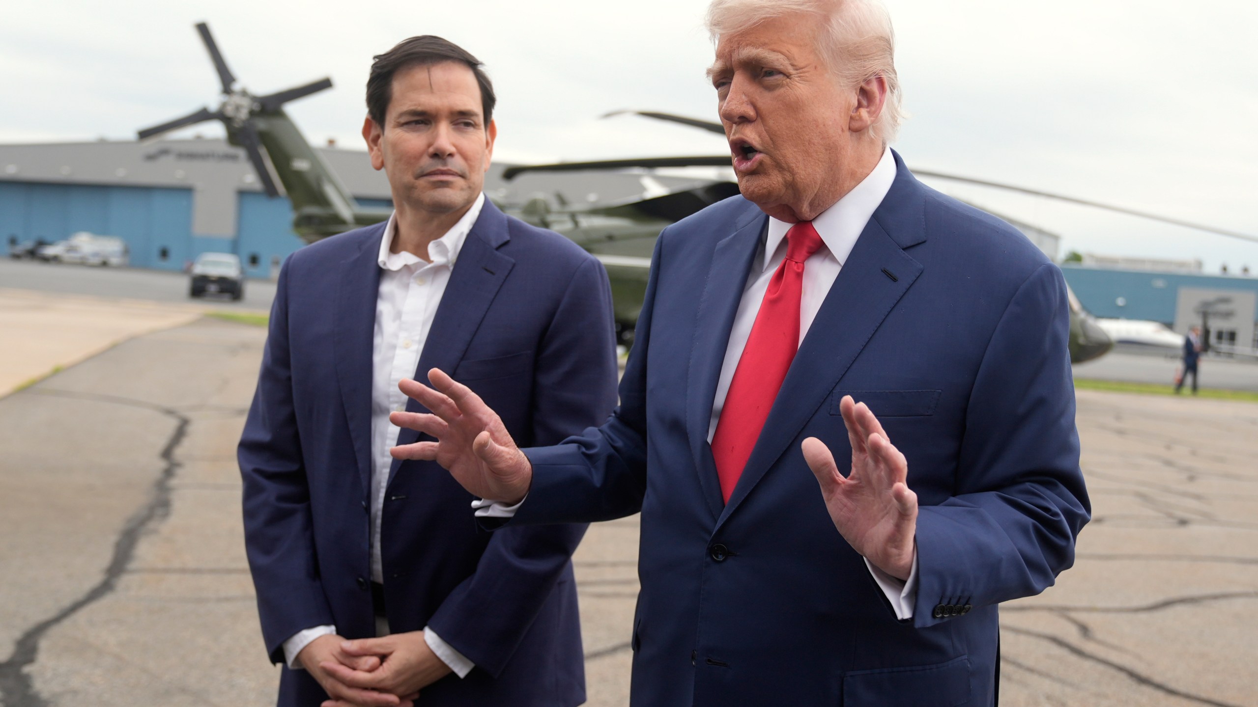 President Donald Trump, right, speaks with reporters as Secretary of State Marco Rubio listens upon arriving at Morristown Municipal Airport in Morristown, N.J., en route to Camp David, Md., Sunday, June 8, 2025. (AP Photo/Manuel Balce Ceneta)
