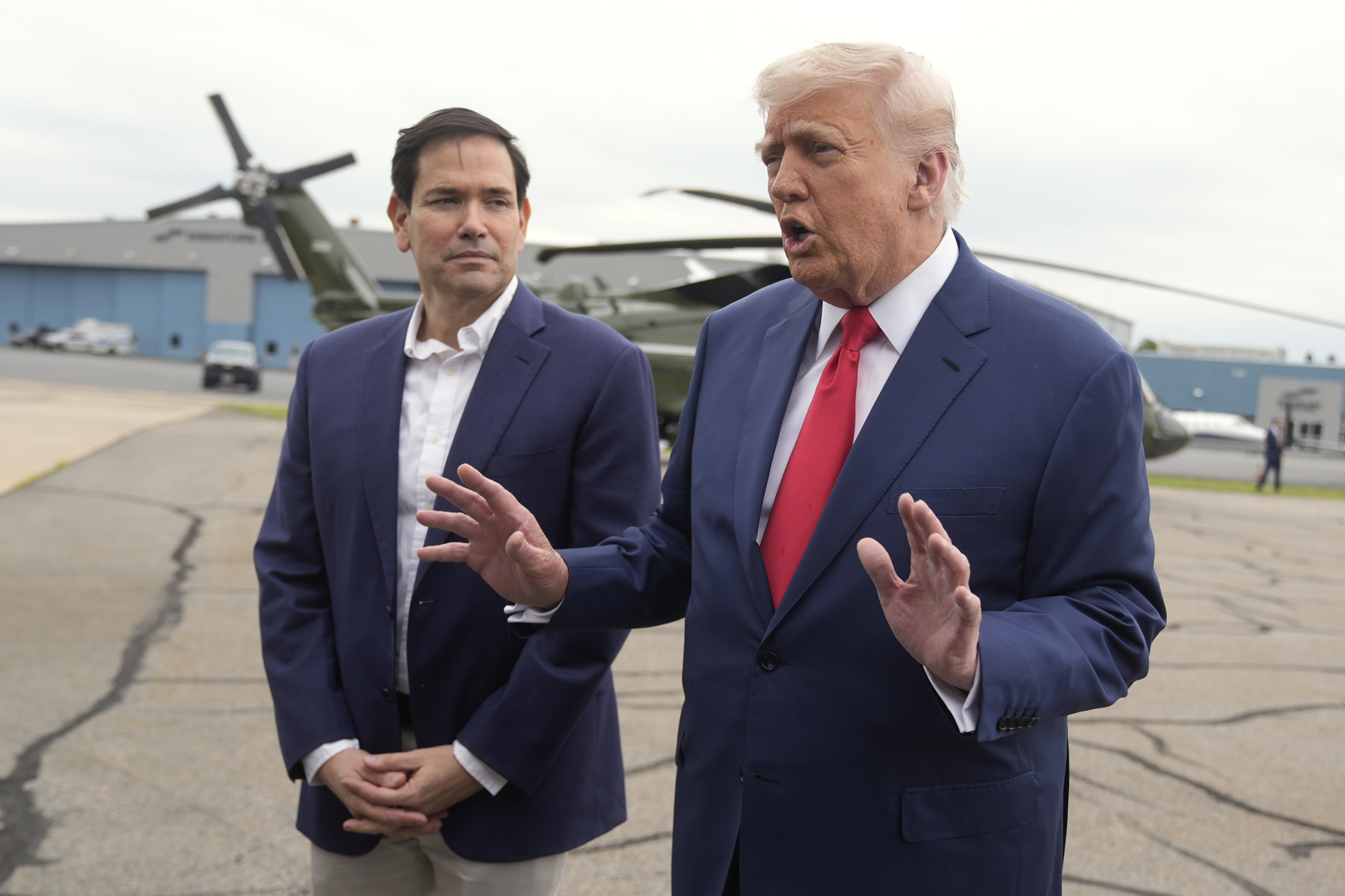 President Donald Trump, right, speaks with reporters as Secretary of State Marco Rubio listens upon arriving at Morristown Municipal Airport in Morristown, N.J., en route to Camp David, Md., Sunday, June 8, 2025. (AP Photo/Manuel Balce Ceneta)