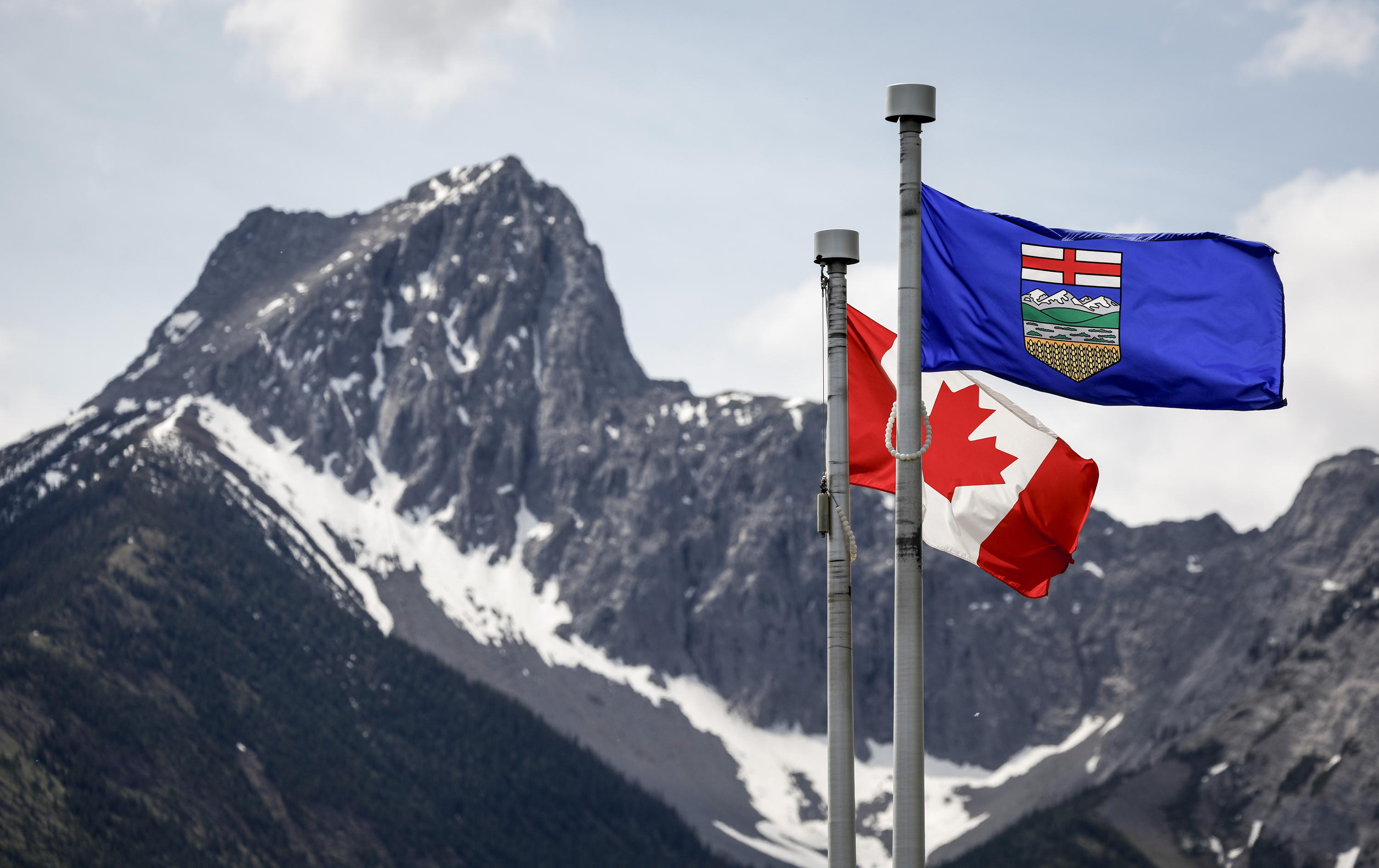 FILE - A Canada flag, left, and an Alberta flag flap in the breeze with Wedge Mountain in the background at the site of the G7 Leaders meeting in Kananaskis, Alberta, June 2, 2025. (Jeff McIntosh/The Canadian Press via AP, file)