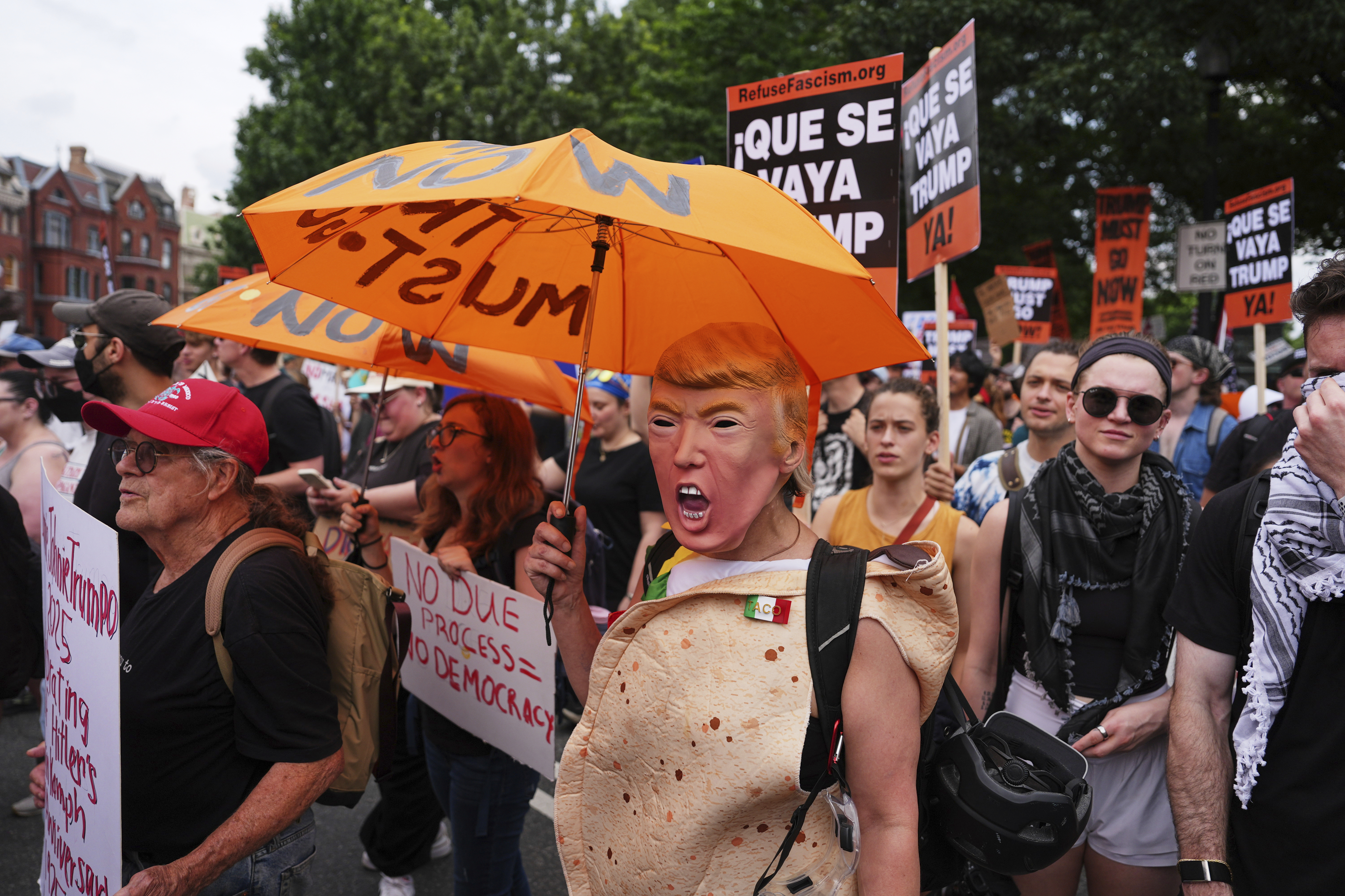 A demonstrator wearing a President Donald Trump mask marches with others during a protest taking place on the day of a military parade commemorating the Army's 250th anniversary, coinciding with President Donald Trump's 79th birthday, Saturday, June 14, 2025, in Washington. (AP Photo/Evan Vucci)