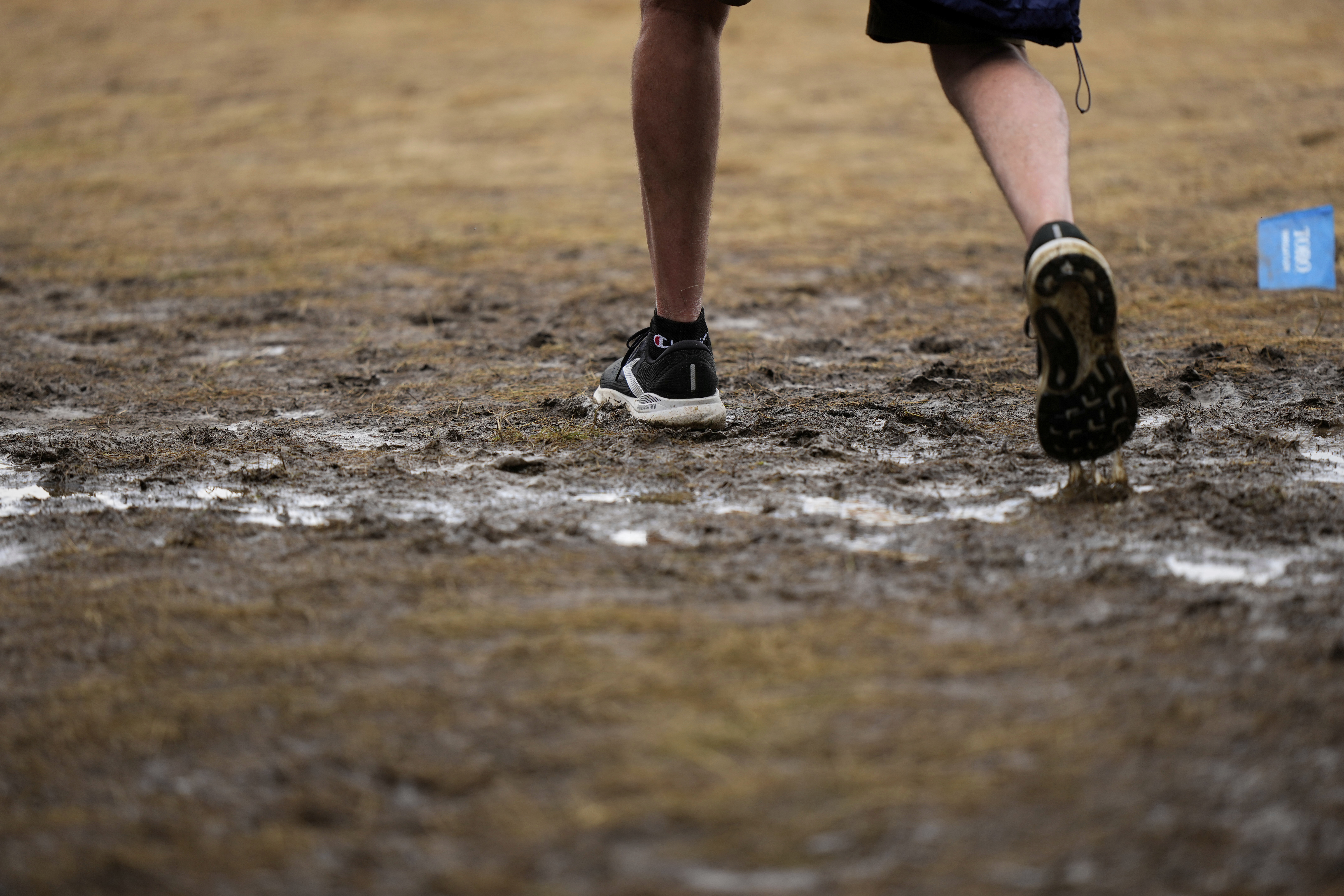 A fan walks through a soggy puddle near the 14th hole during the third round of the U.S. Open golf tournament at Oakmont Country Club Saturday, June 14, 2025, in Oakmont, Pa. (AP Photo/Charlie Riedel)
