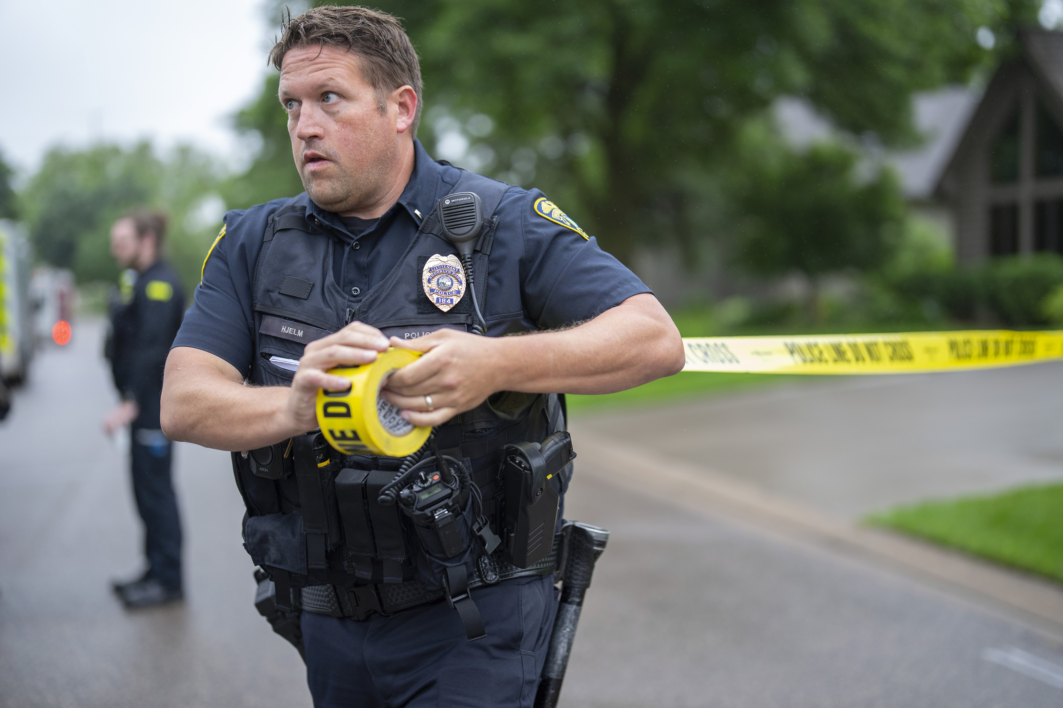 Brooklyn Park Police Lieutenant Hjelm sets up a perimeter with police tape near the scene of a shooting in Brooklyn Park, Minn. on Saturday, June 14, 2025. (Alex Kormann/Star Tribune via AP)
