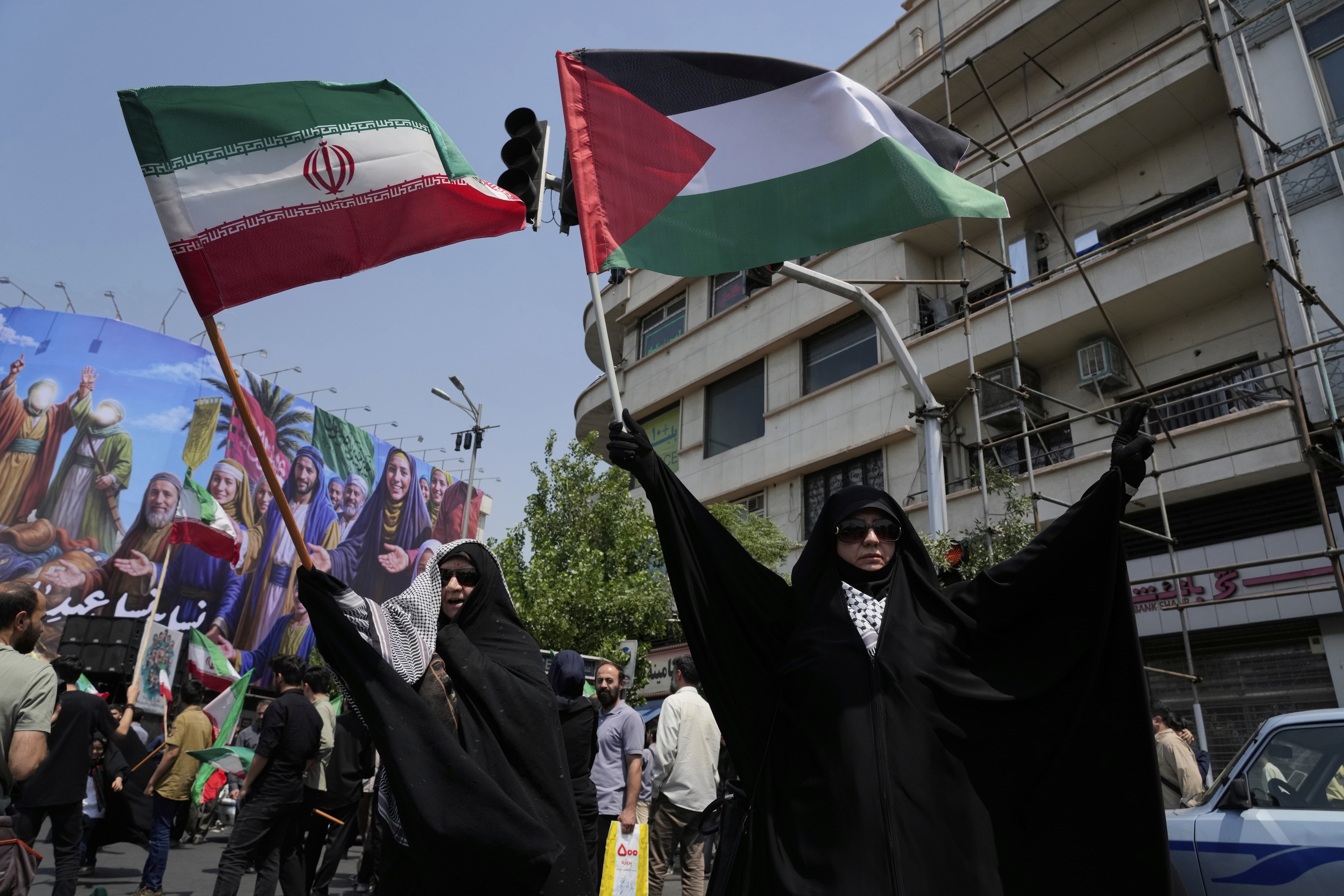 Iranian protesters hold up Iranian and Palestinian flags in an anti-Israeli gathering in Tehran, Iran, Friday, June 13, 2025. (AP Photo/Vahid Salemi)