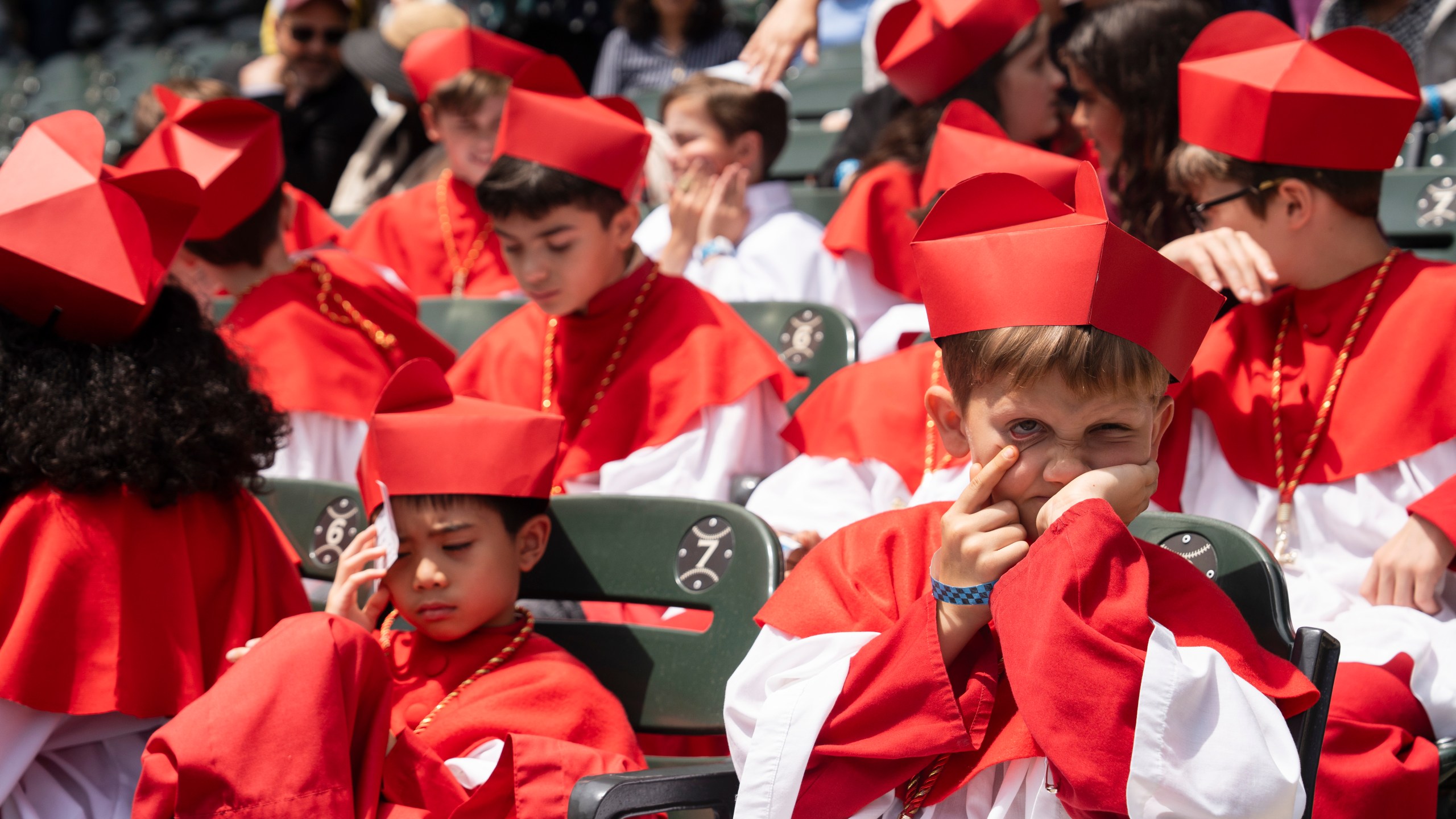 Students of Our Lady of Mt. Carmel Academy, who held a mock conclave before, wear cardinals' vestments during the Archdiocese of Chicago's celebration of Pope Leo XIV at Rate Field, Saturday, June 14, 2025. (Pat Nabong/Chicago Sun-Times via AP)