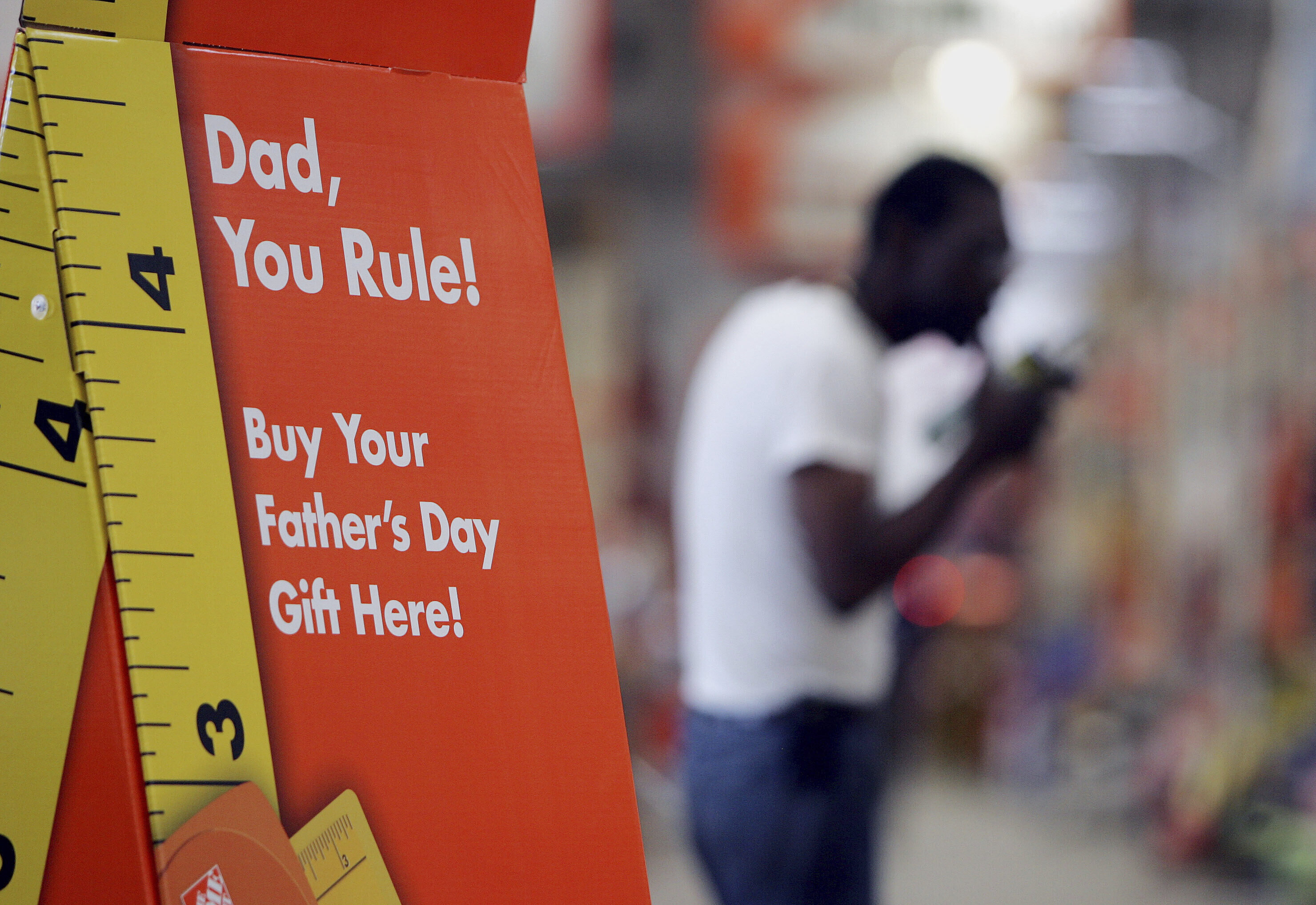 FILE - A sign advertises Father's Day gifts as a shopper buys building materials in the background at Atlanta Home Depot store, June 8 , 2006. (AP Photo/John Bazemore, File)