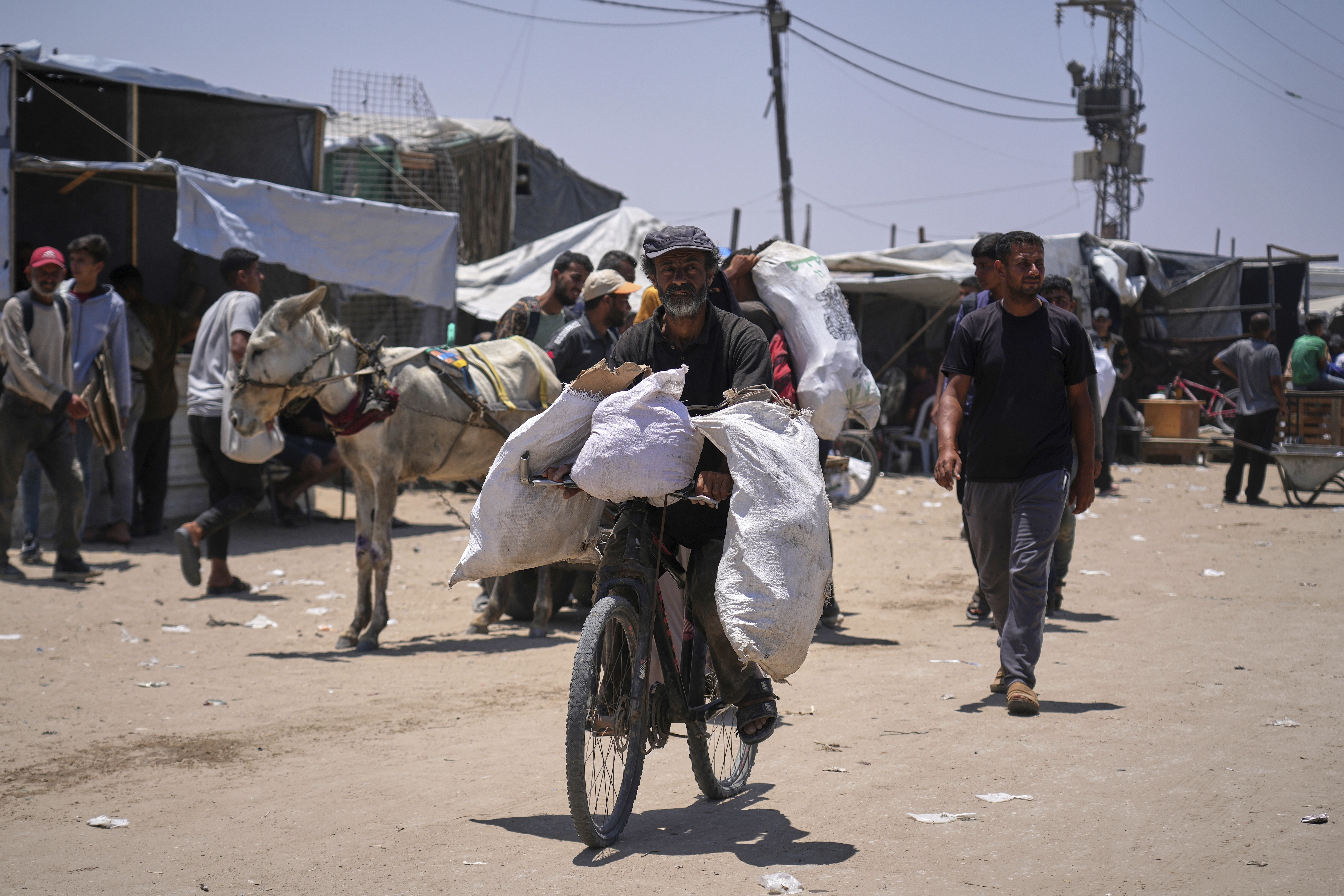 Palestinians carry bags containing food and humanitarian aid packages delivered by the Gaza Humanitarian Foundation, a U.S.-backed organization, in Rafah, southern Gaza Strip, Sunday, June 15, 2025. (AP Photo/Abdel Kareem Hana)