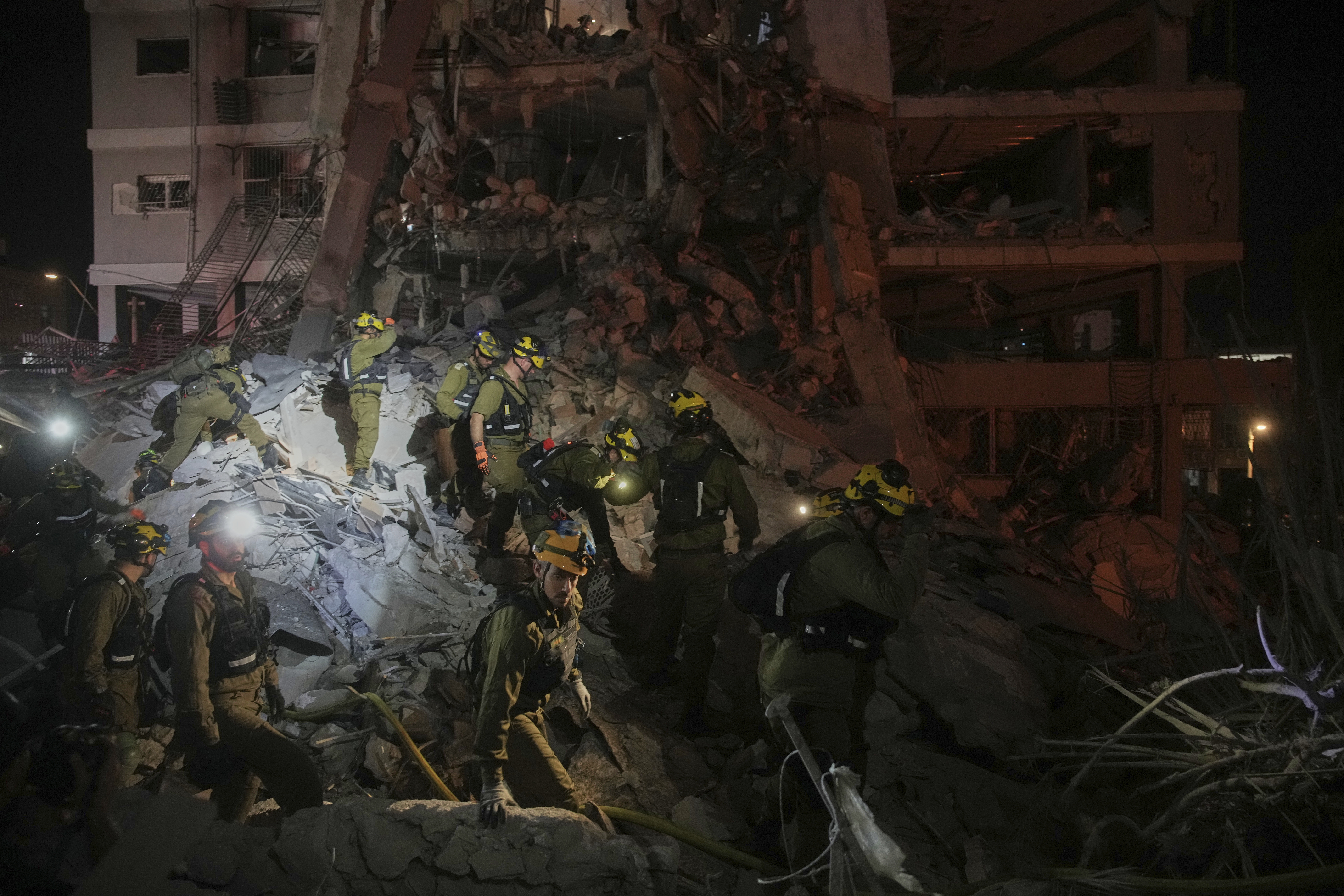 Israeli security forces inspect destroyed buildings that were hit by a missile fired from Iran, near Tel Aviv, Israel, Sunday, June 15, 2025. (AP Photo/Ohad Zwigenberg)