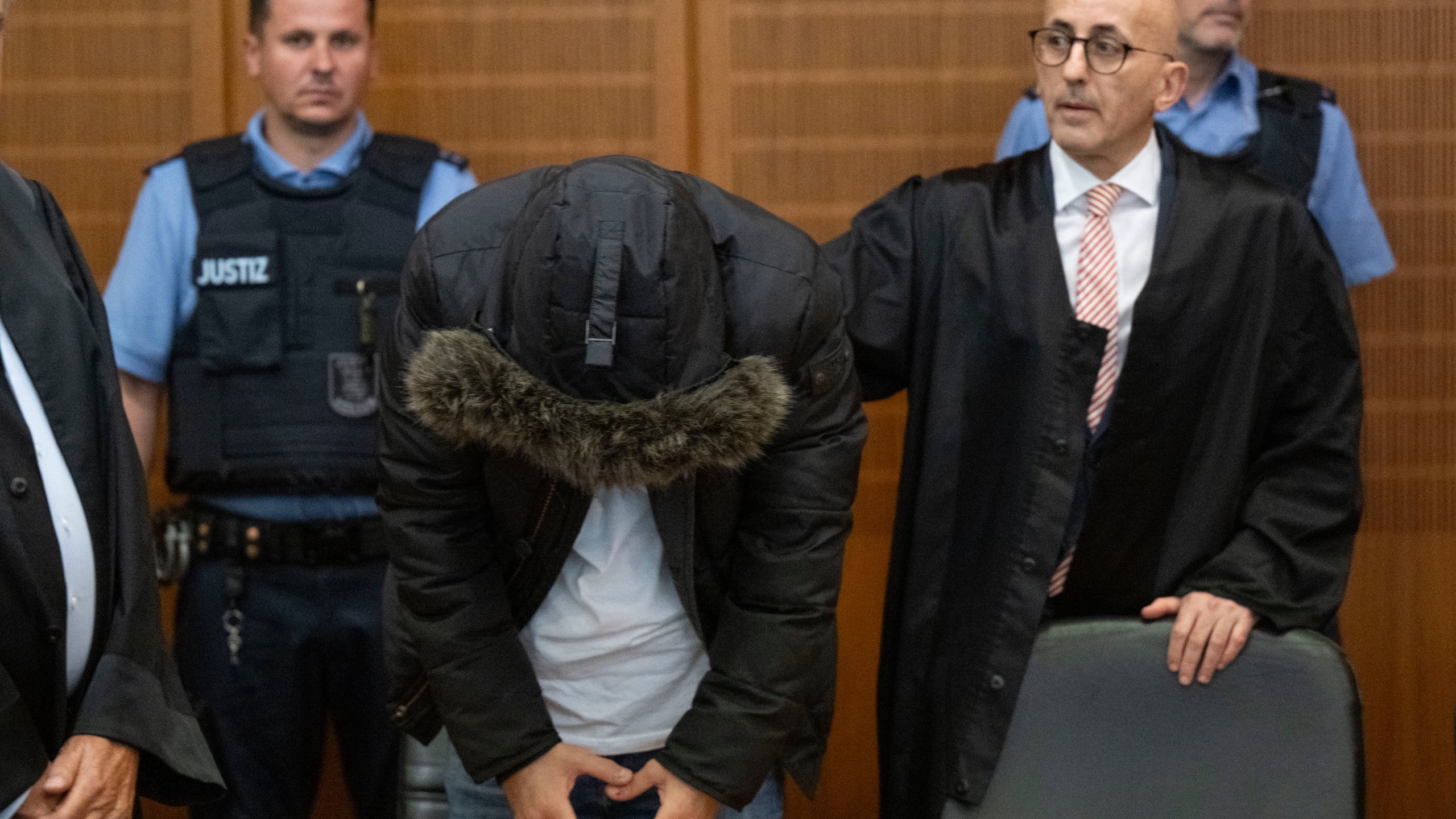 A Syrian doctor, center, accused of torture and war crimes in his Syrian homeland, stands next to his lawyer Oussama Al-Agi, right, in the Higher Regional Court before the verdict is announced in Frankfurt, Germany, Monday, June 16, 2025. (Boris Roessler/dpa via AP)