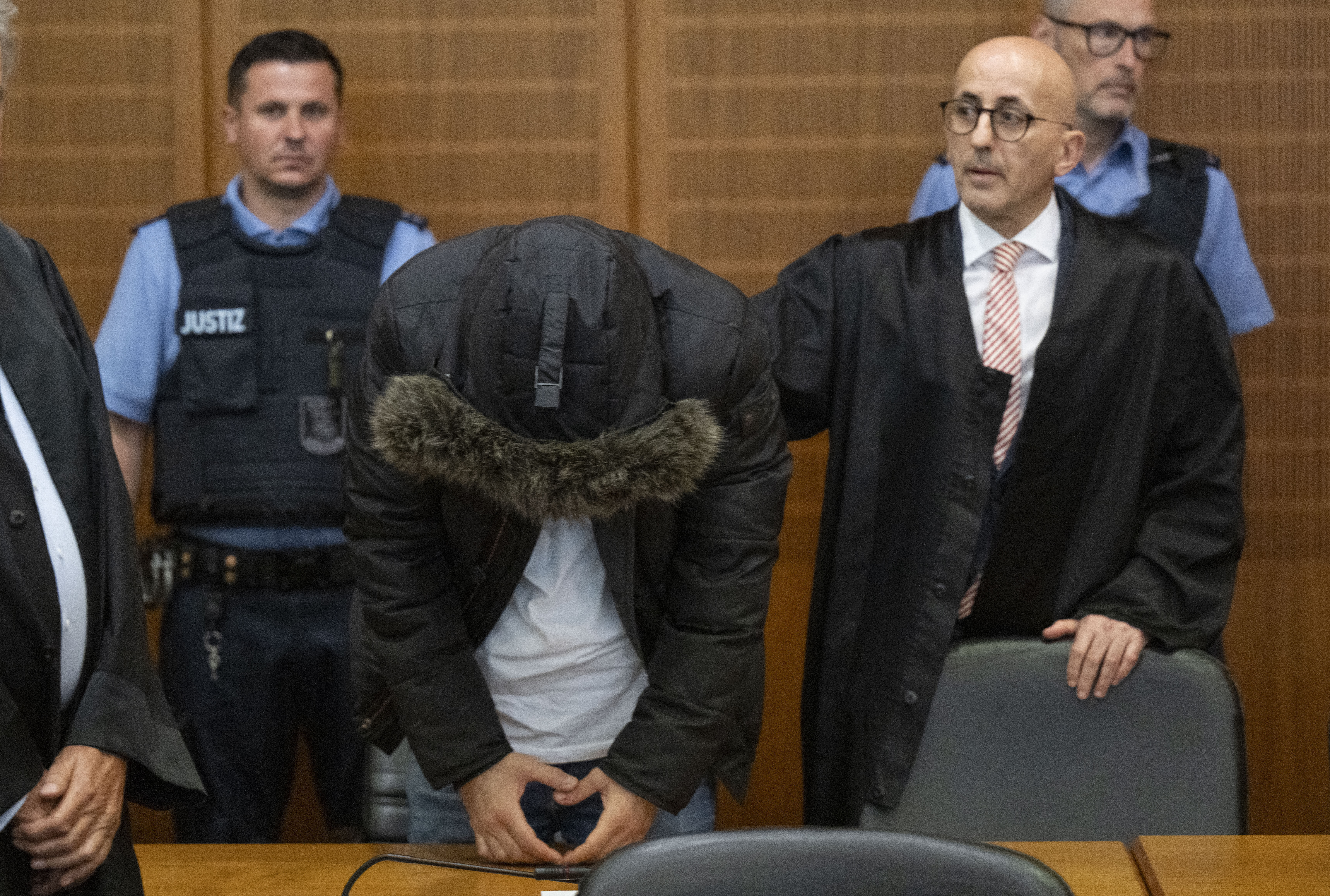 A Syrian doctor, center, accused of torture and war crimes in his Syrian homeland, stands next to his lawyer Oussama Al-Agi, right, in the Higher Regional Court before the verdict is announced in Frankfurt, Germany, Monday, June 16, 2025. (Boris Roessler/dpa via AP)