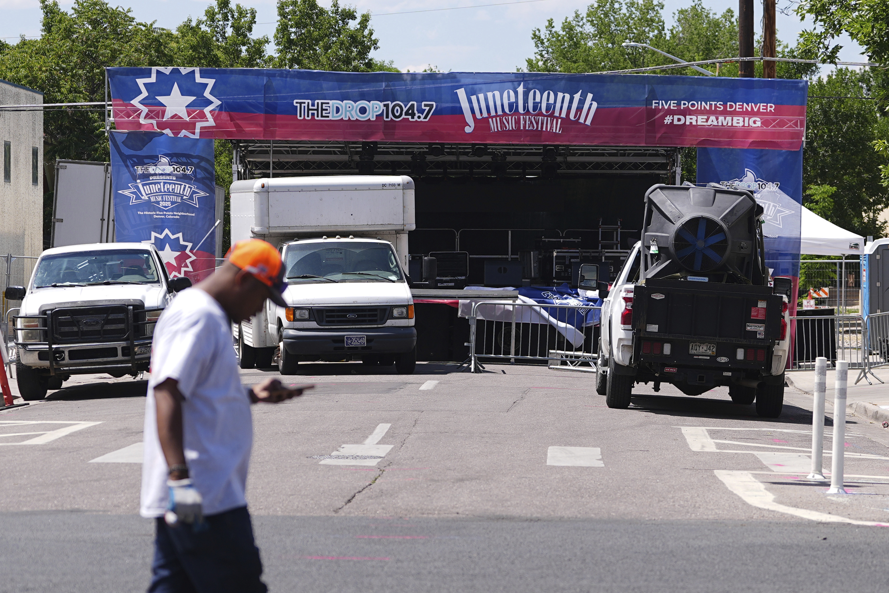 Volunteer passes by the stage for musical acts to perform at the Juneteenth celebration in the Five Points neighborhood where the event is staged Saturday, June 14, 2025, in Denver. (AP Photo/David Zalubowski)