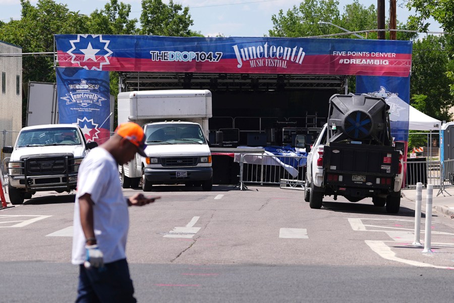 Volunteer passes by the stage for musical acts to perform at the Juneteenth celebration in the Five Points neighborhood where the event is staged Saturday, June 14, 2025, in Denver. (AP Photo/David Zalubowski)